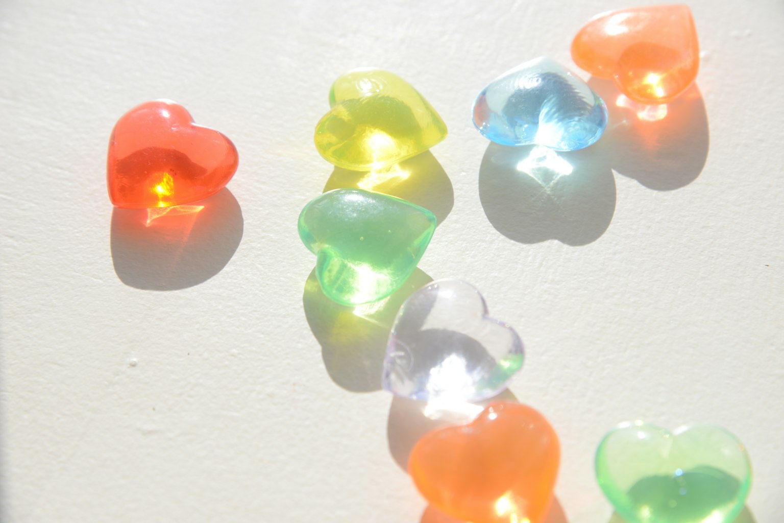 Caramelos de gelatina en forma de corazón de colores esparcidos sobre un fondo blanco