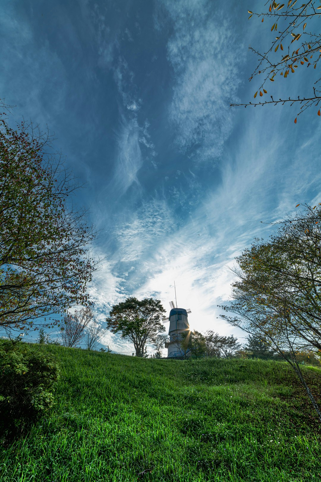 chimney on a grassy hill under blue sky clouds