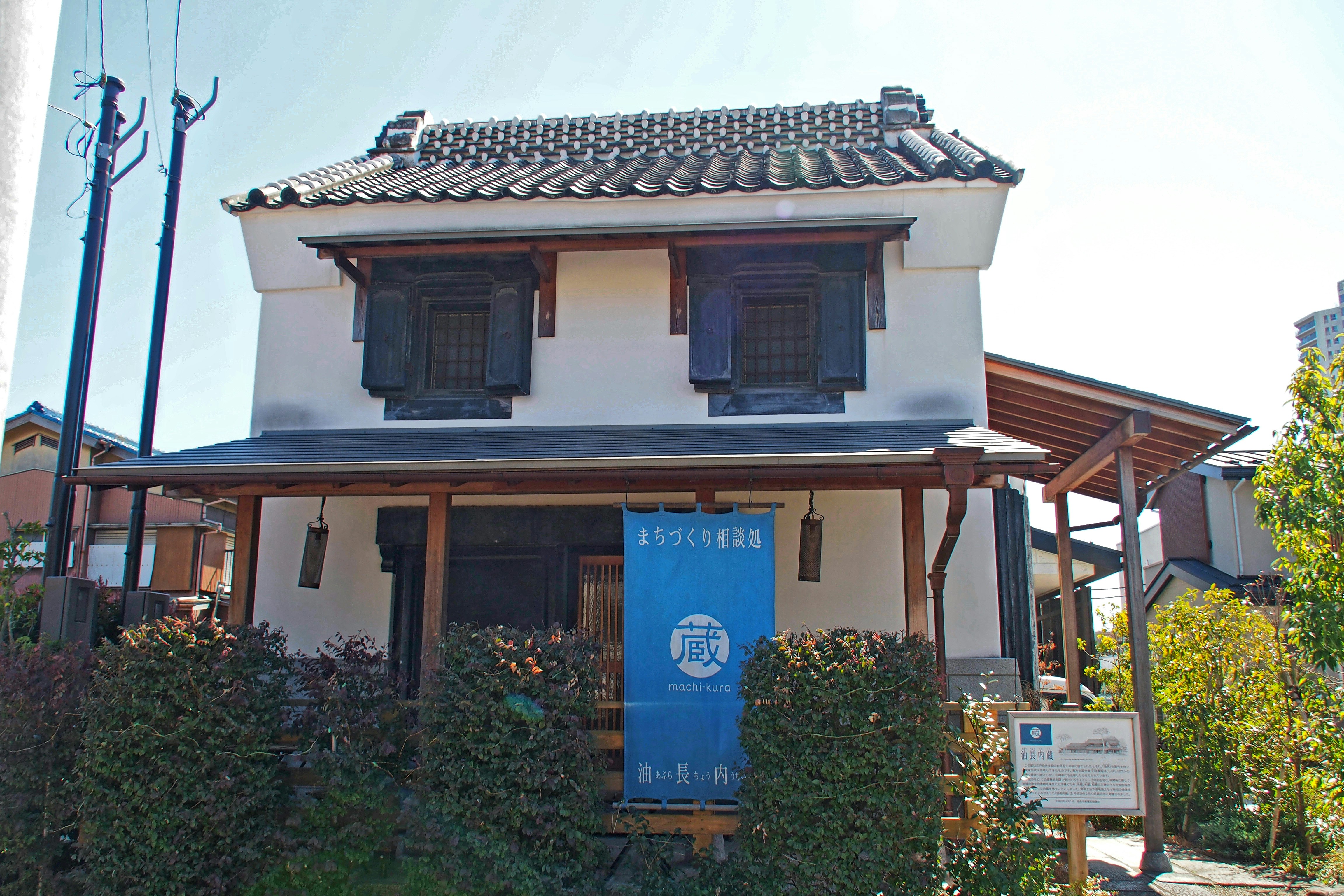 Piccola casa tradizionale in stile machiya con tetto in tegole e cartelli all’ingresso
