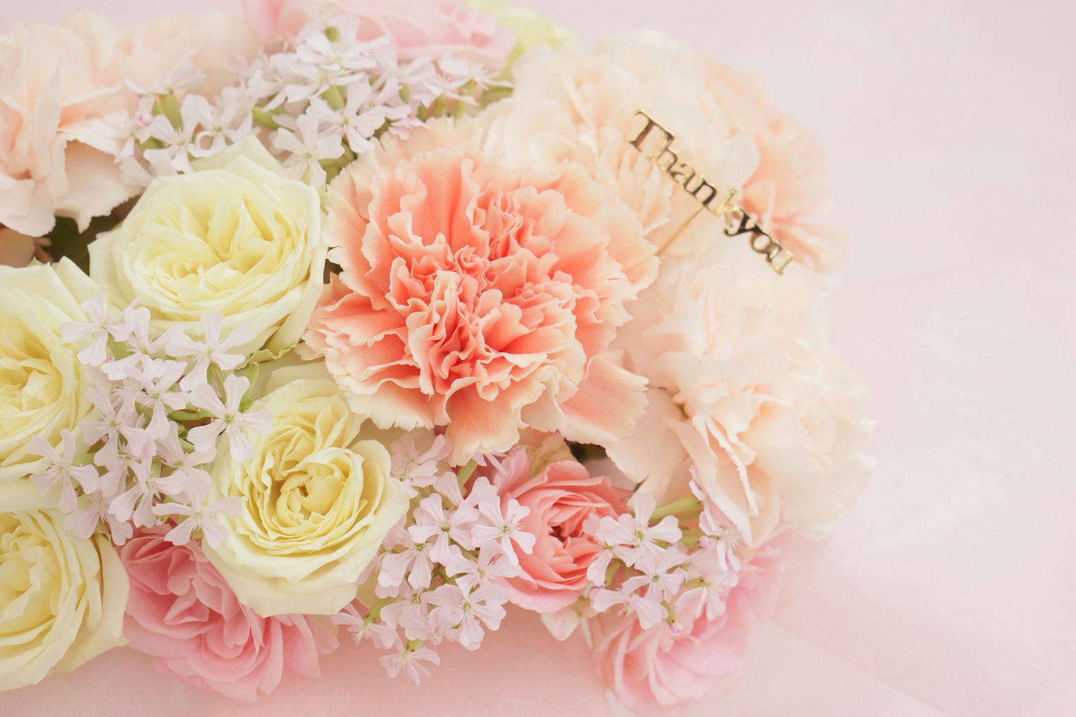 An arrangement of soft-colored flowers including roses and carnations