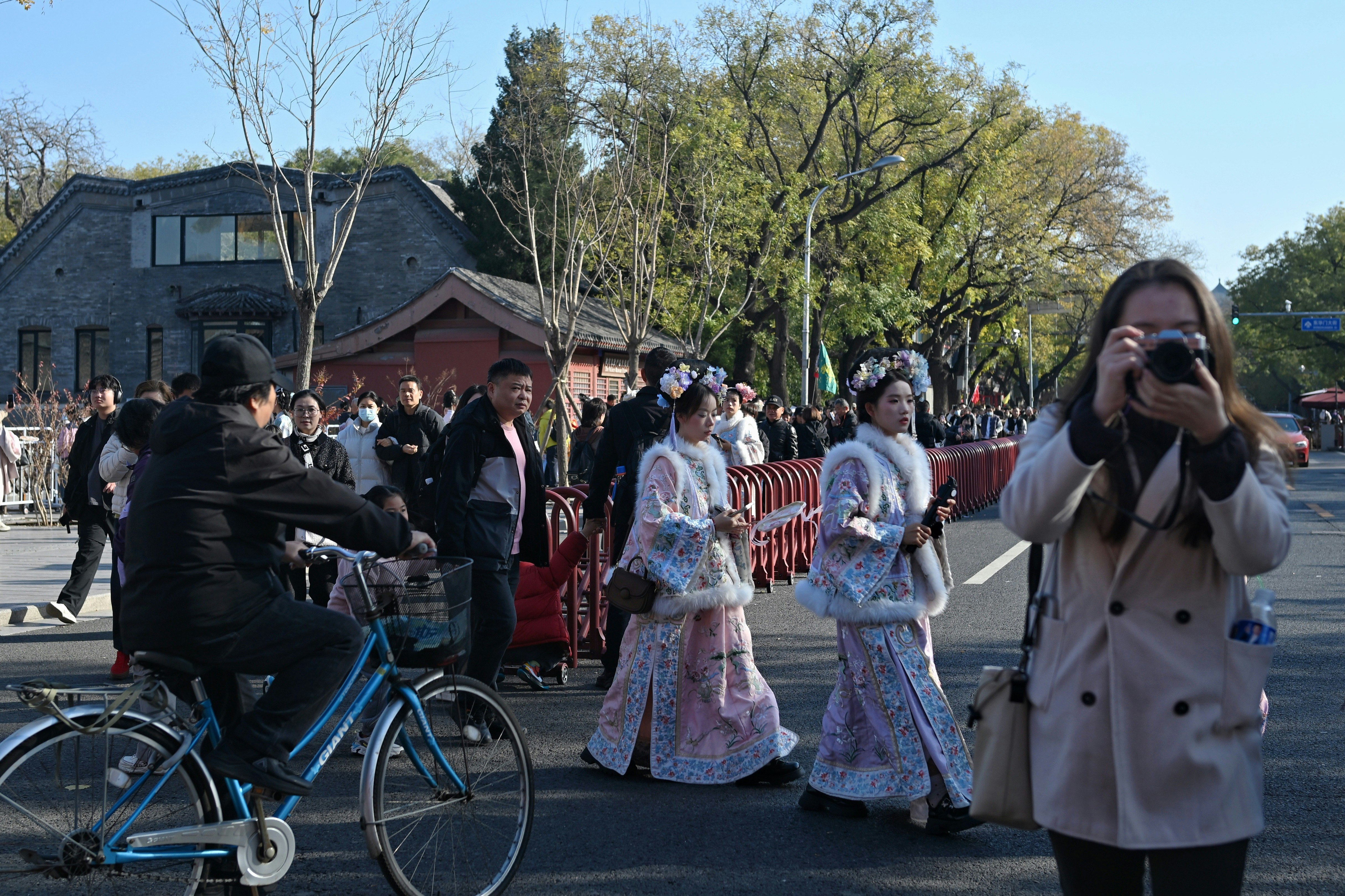 伝統的な衣装を着た人々が通りを歩いている風景 自転車に乗った人もいる