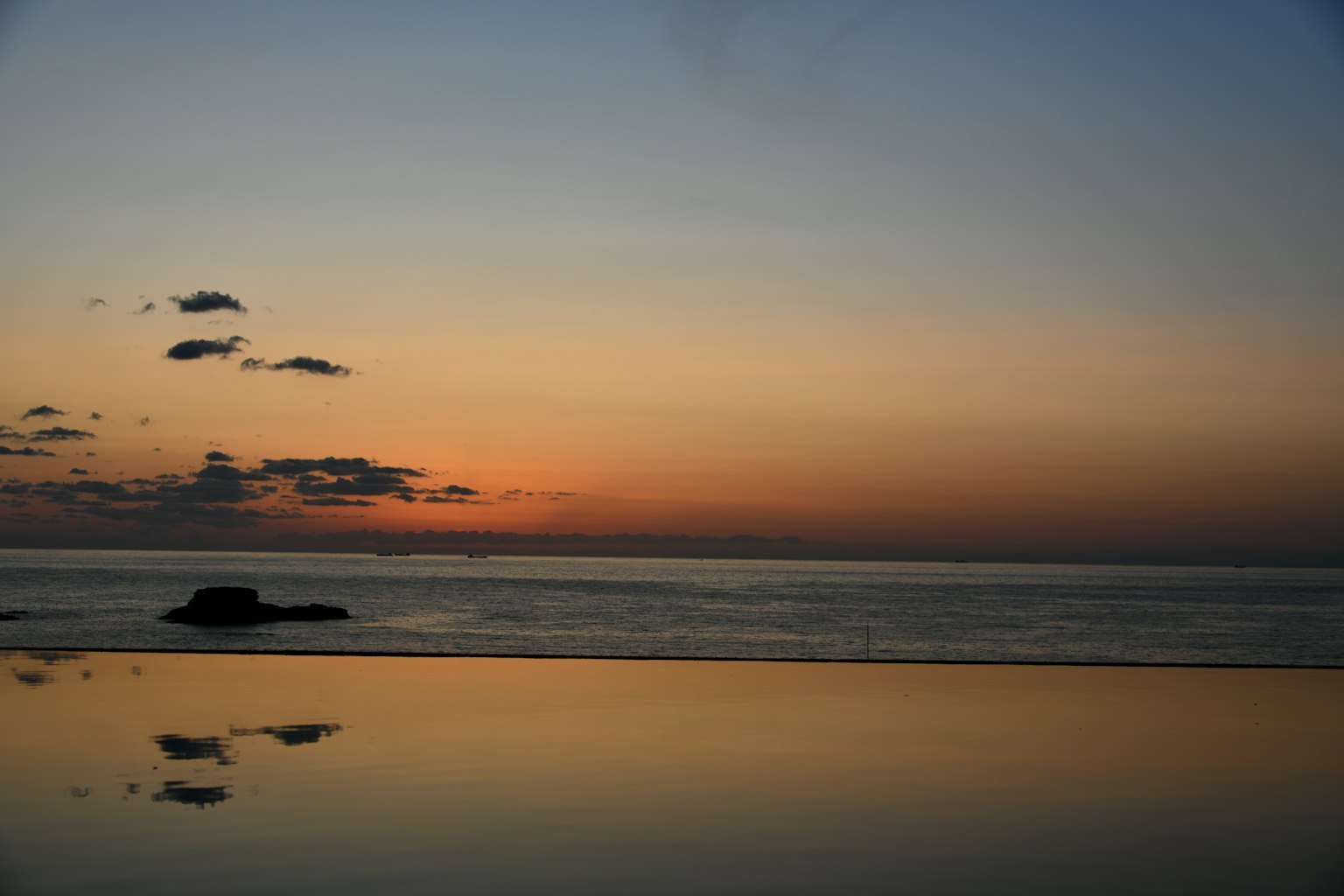 Ruhiges Meer spiegelt einen Sonnenuntergangshimmel
