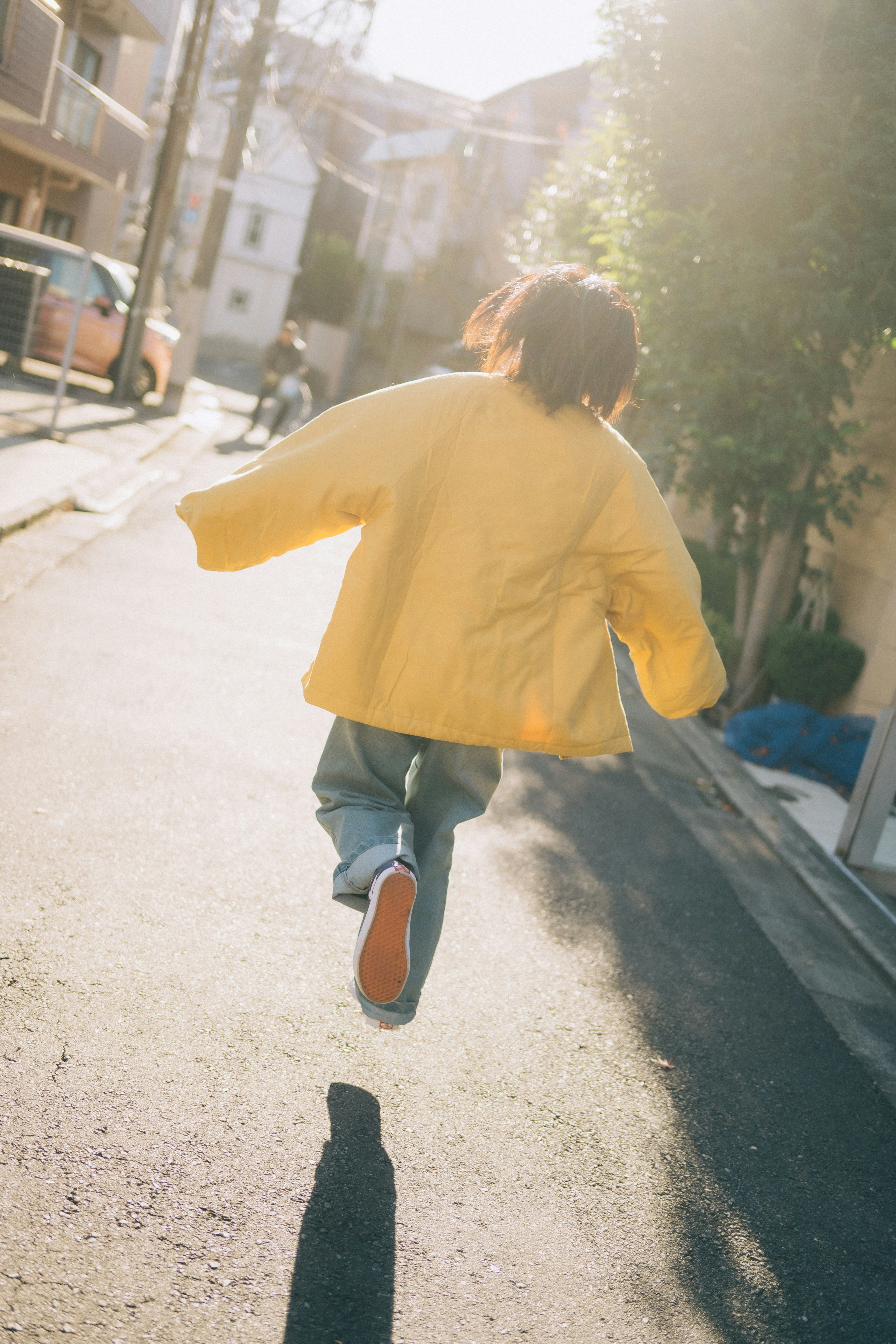 日差しの差す路地を走る子どもの後ろ姿