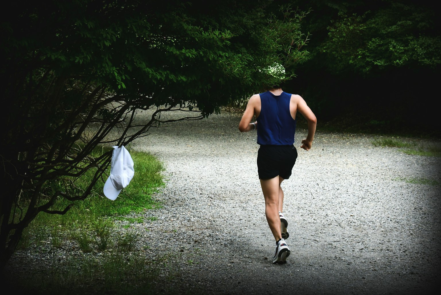 Un uomo che corre su un sentiero di ghiaia in un'area boschiva