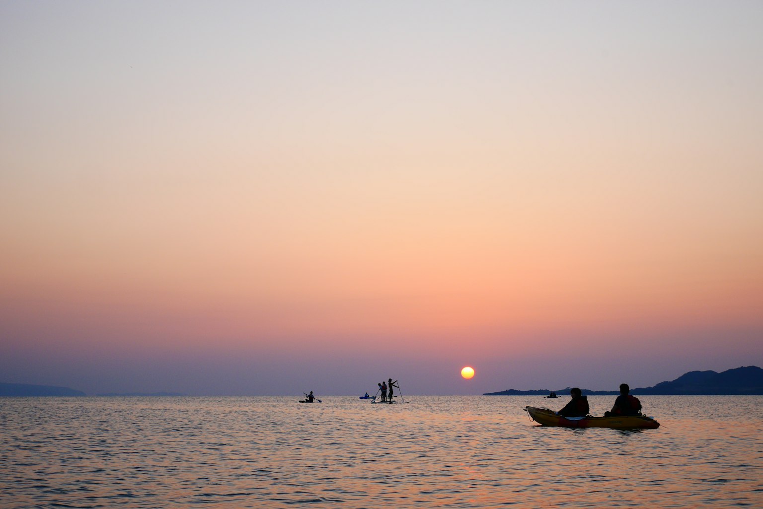 日落时分在海上划皮艇的人影