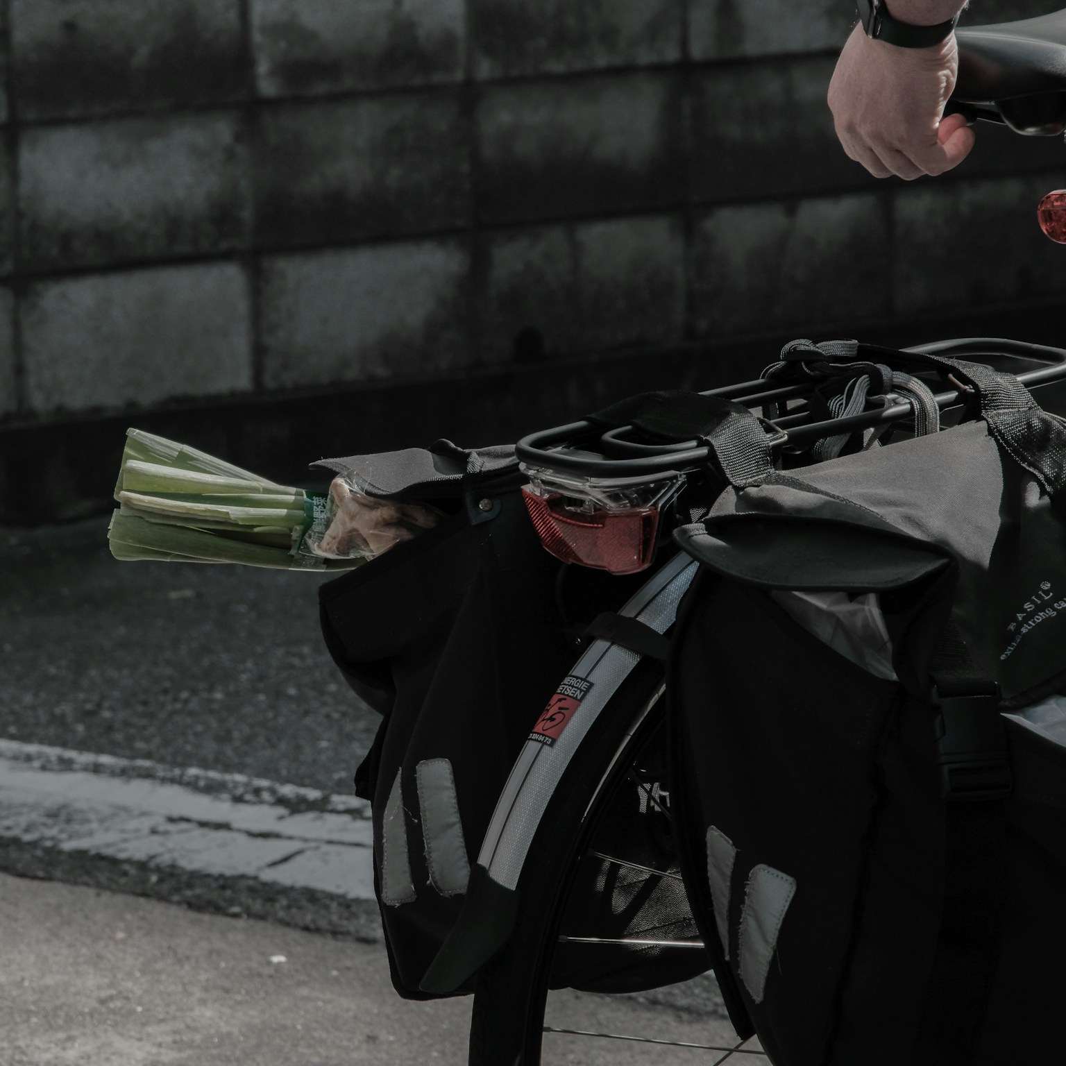 Bicycle saddlebag with vegetables and a hand holding the bag