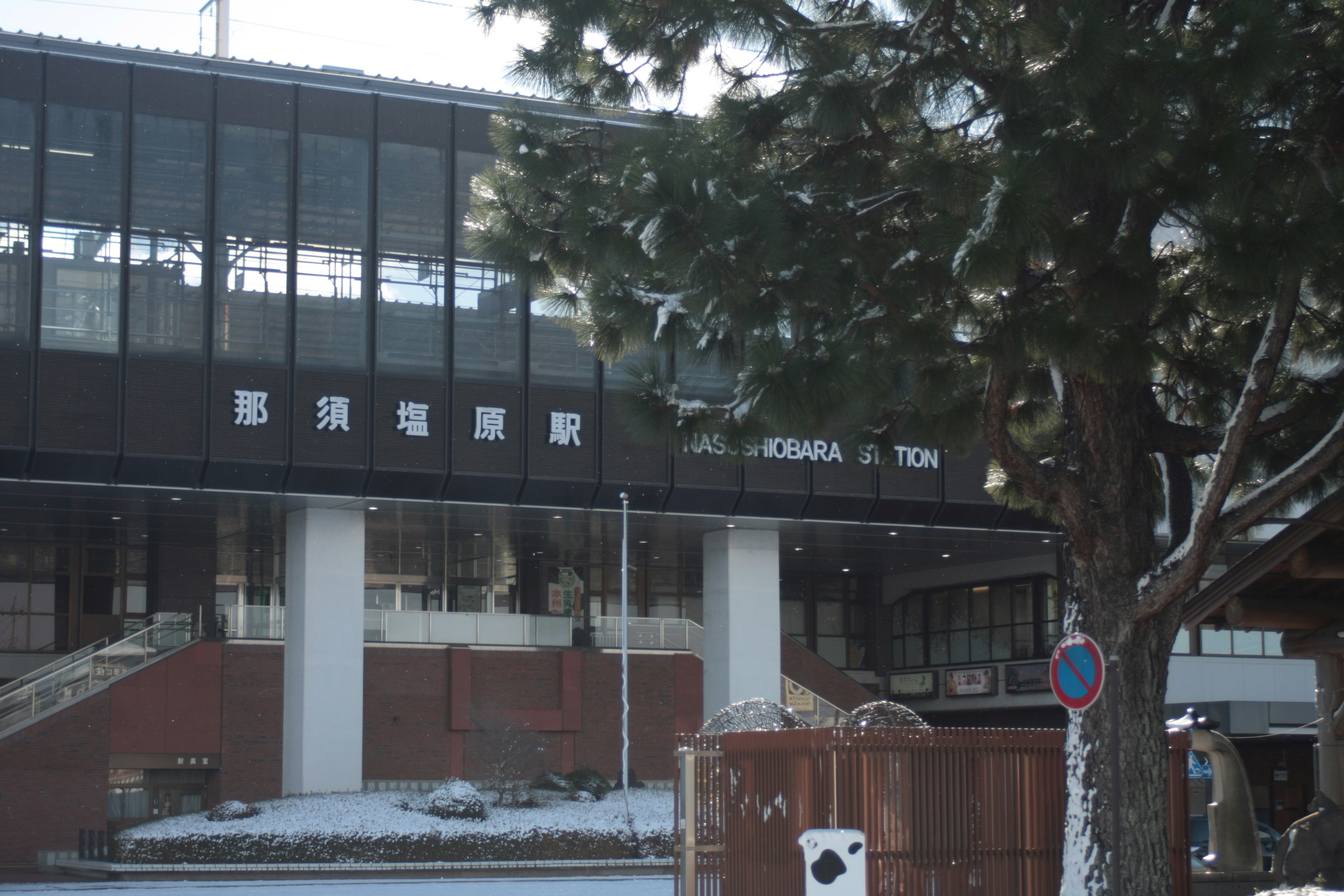 有樹木與殘雪的玻璃車站建築