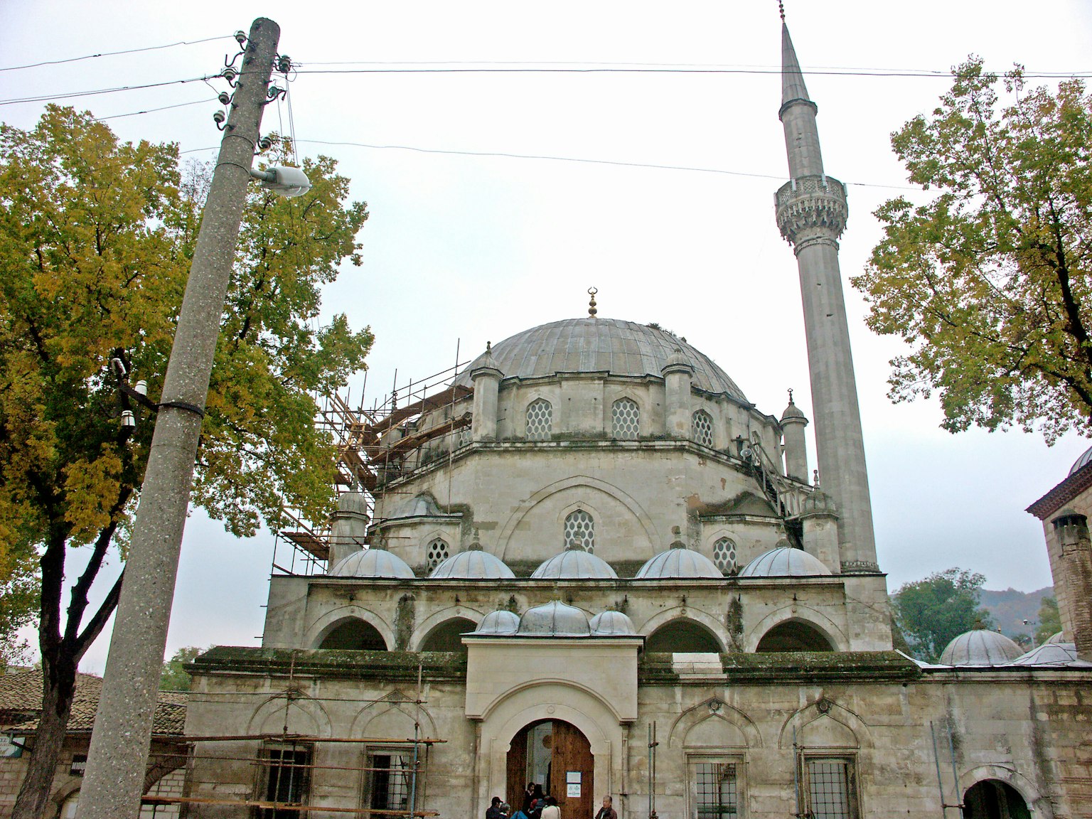 Facciata di una vecchia moschea con un minareto e alberi circostanti