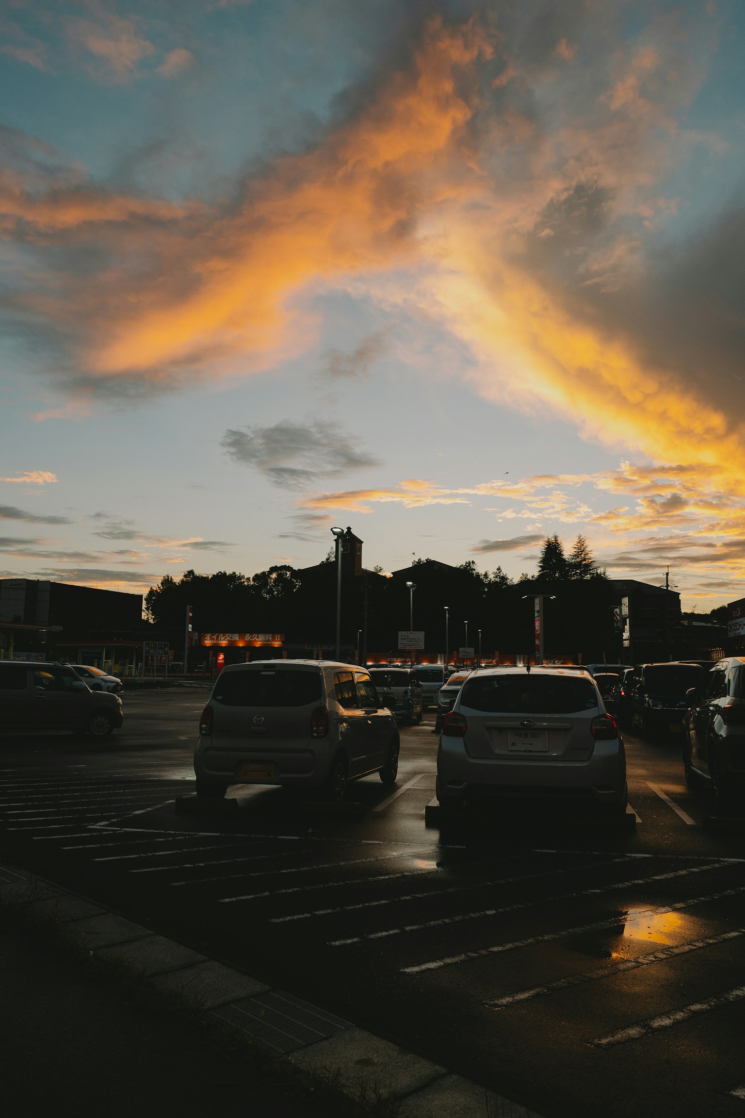 Un ciel de coucher de soleil avec des nuages colorés au-dessus d'un parking rempli de voitures