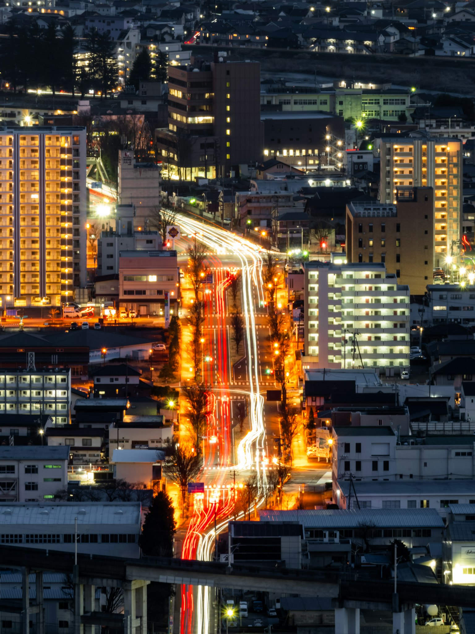 Paisaje urbano nocturno con edificios brillantes y luces de coches
