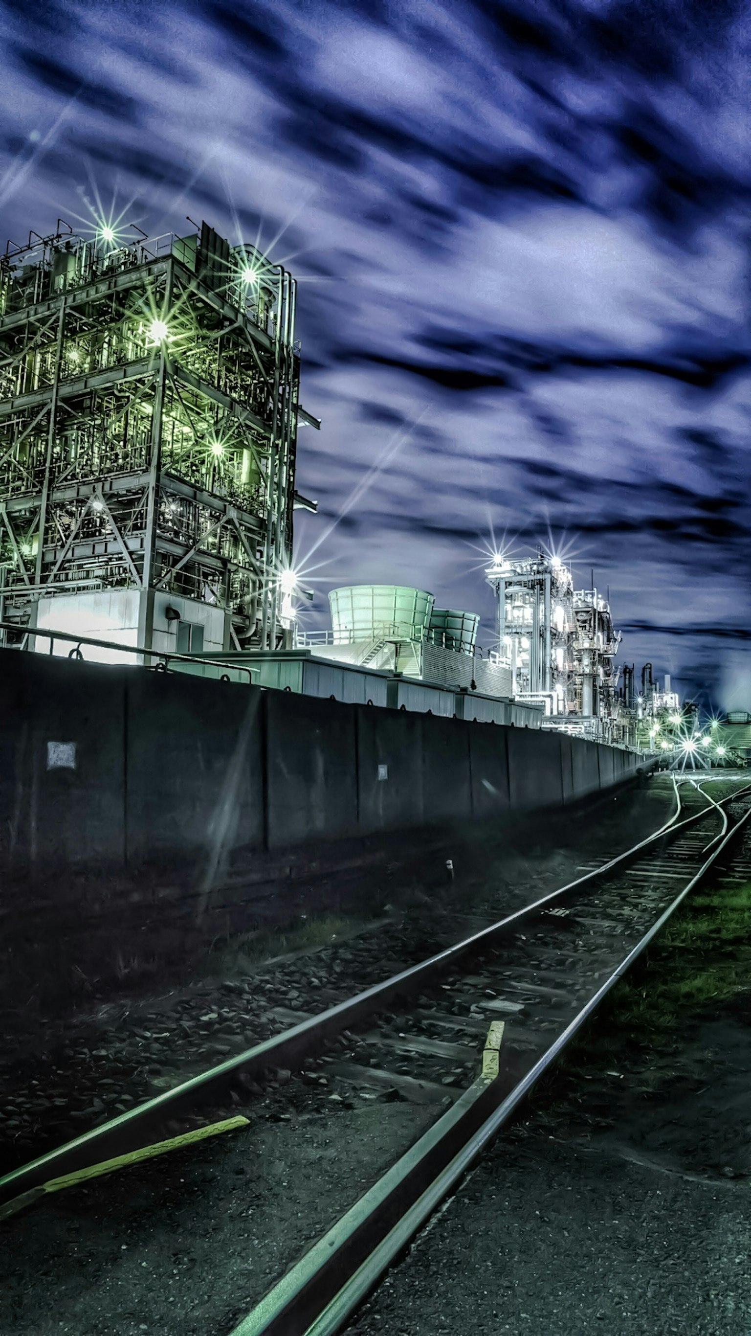 Night view featuring industrial structures and railway tracks