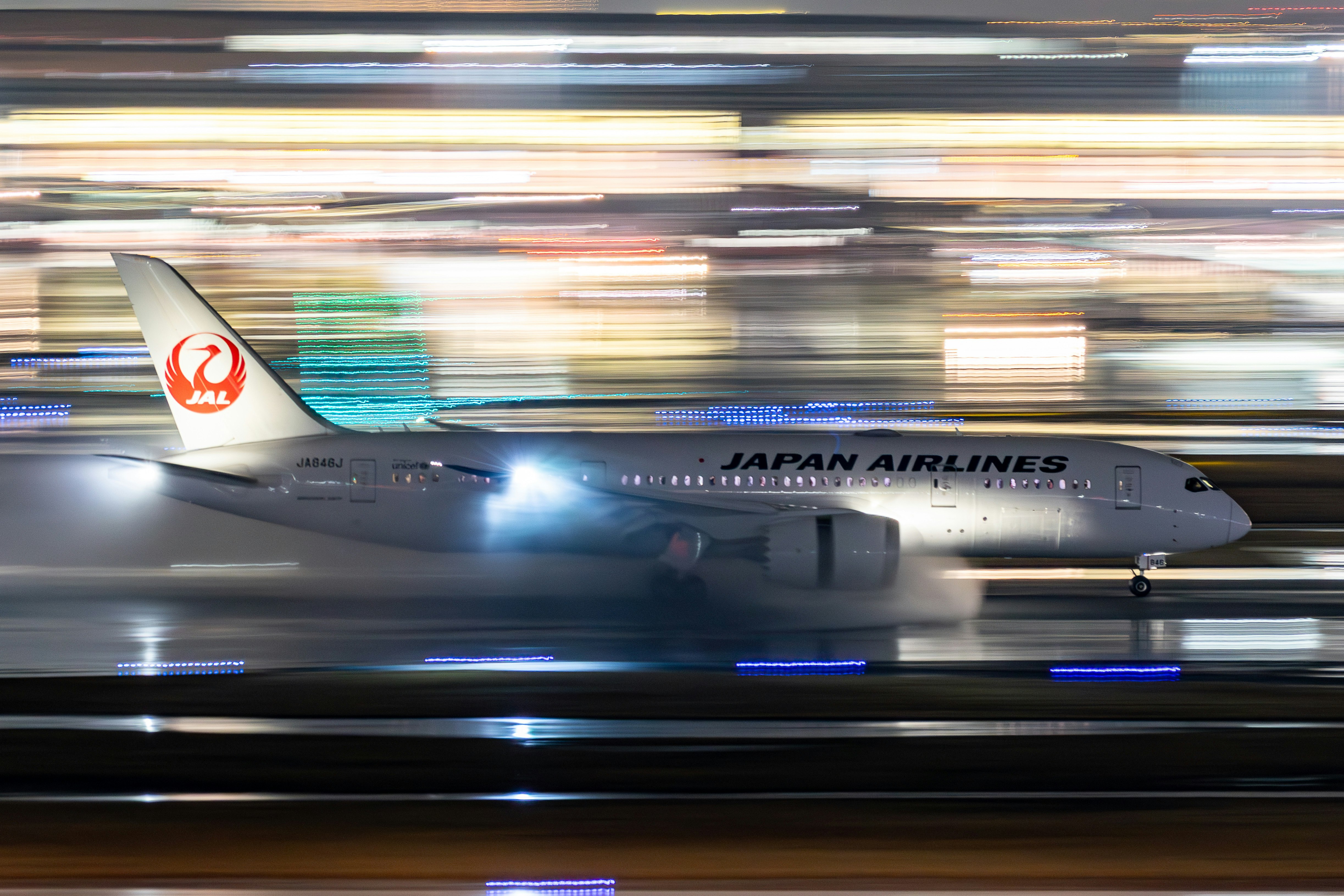 雨の羽田空港で流し撮りされた着陸機の夜景