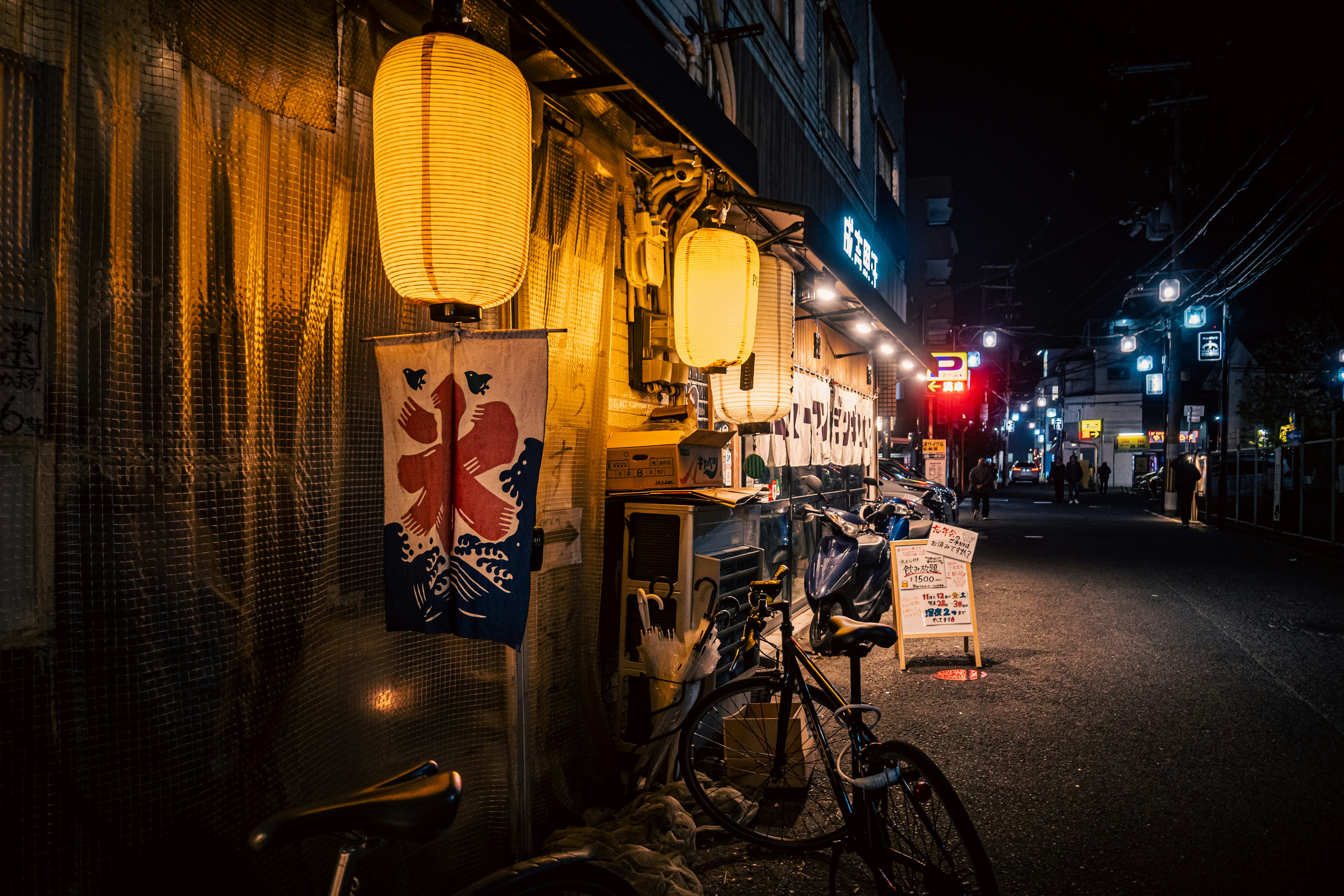 夜の路地に並ぶ自転車と提灯の灯り
