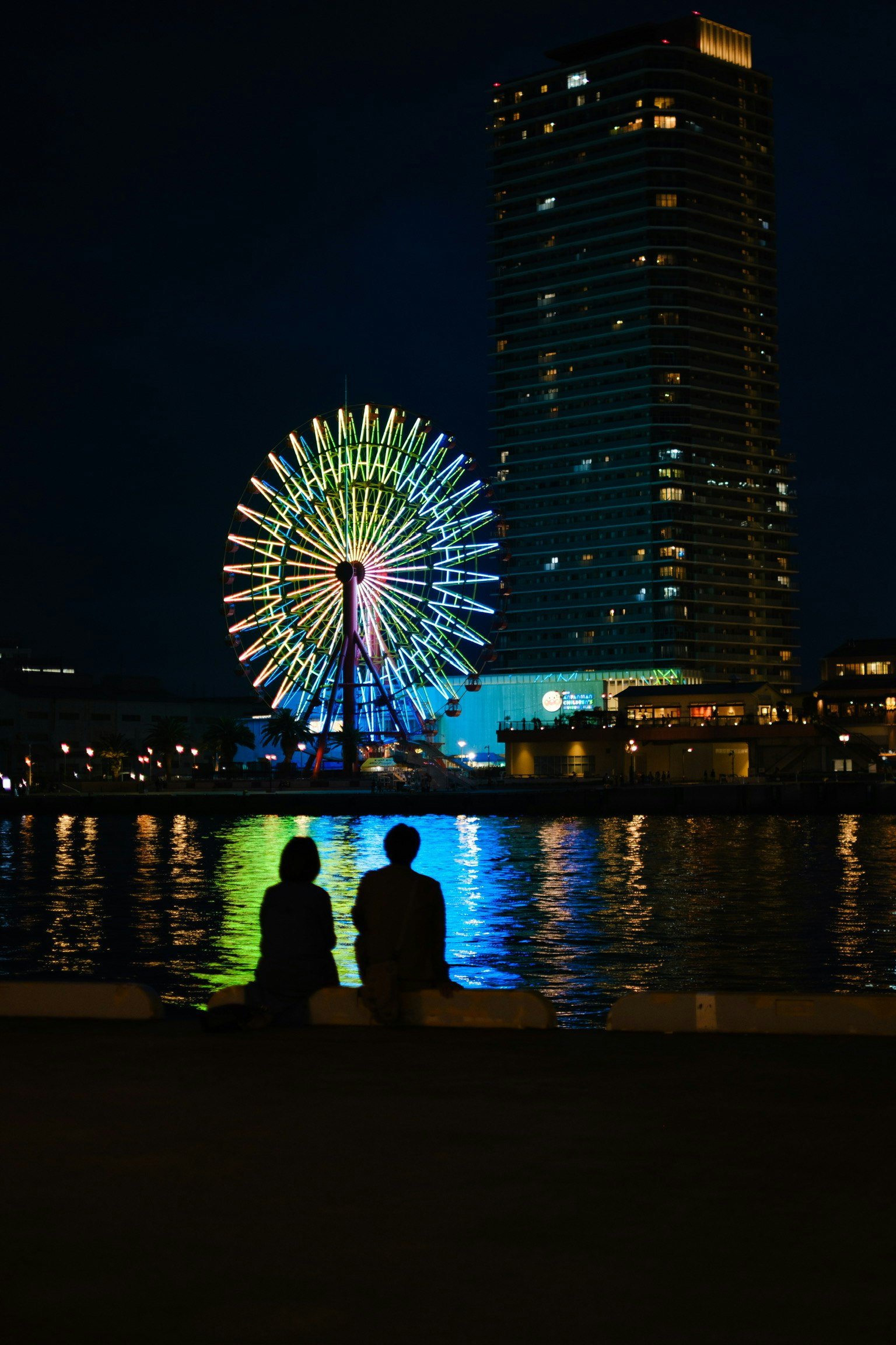 夜の観覧車と高層ビルを背景にしたカップルのシルエット