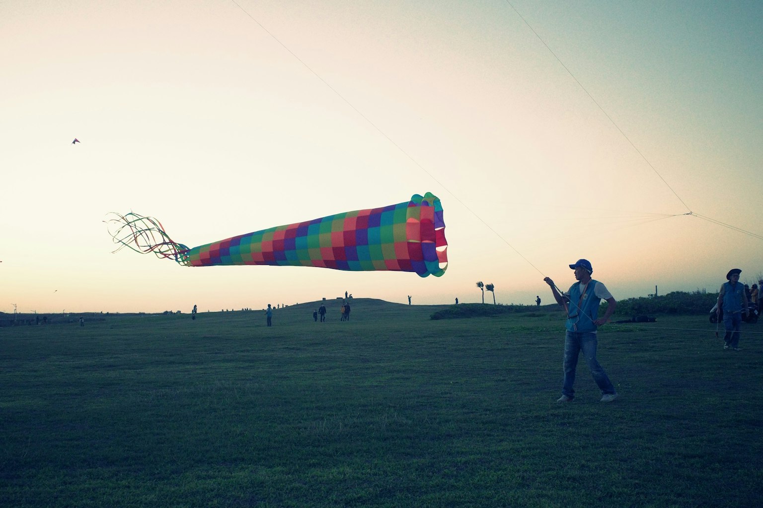 カラフルな凧を持っている人が広い草原で遊んでいる風景