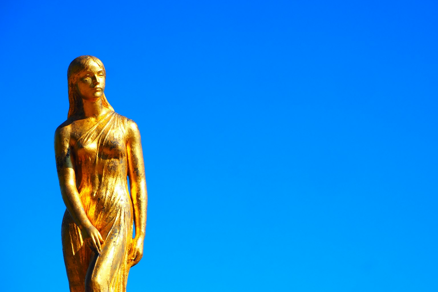 Estatua dorada de pie bajo un cielo azul
