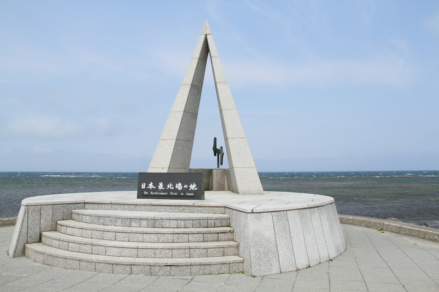 Monumento triangular con estatua junto a la costa