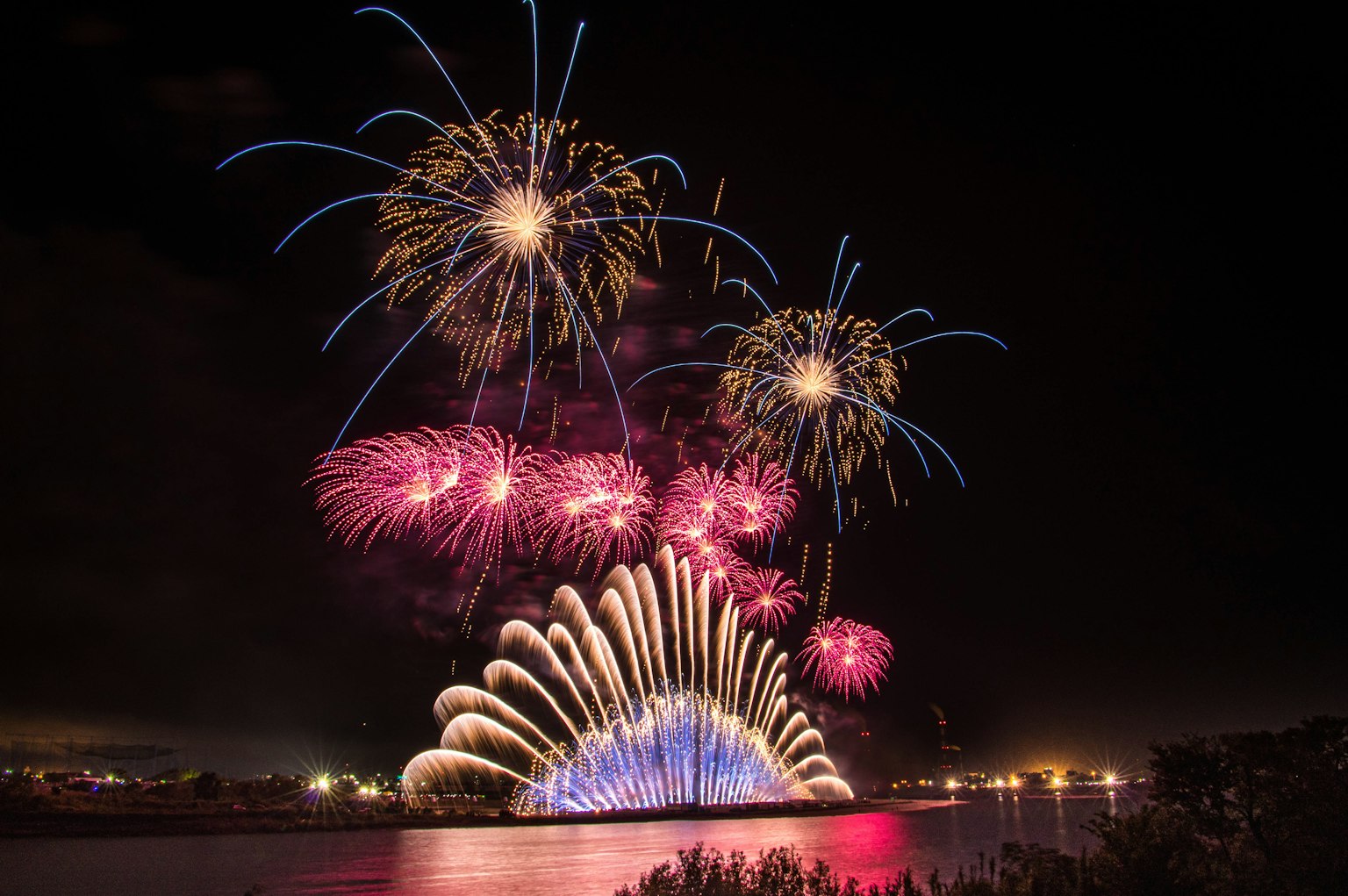 Spettacolo di fuochi d'artificio vibranti nel cielo notturno luci colorate che si riflettono sull'acqua
