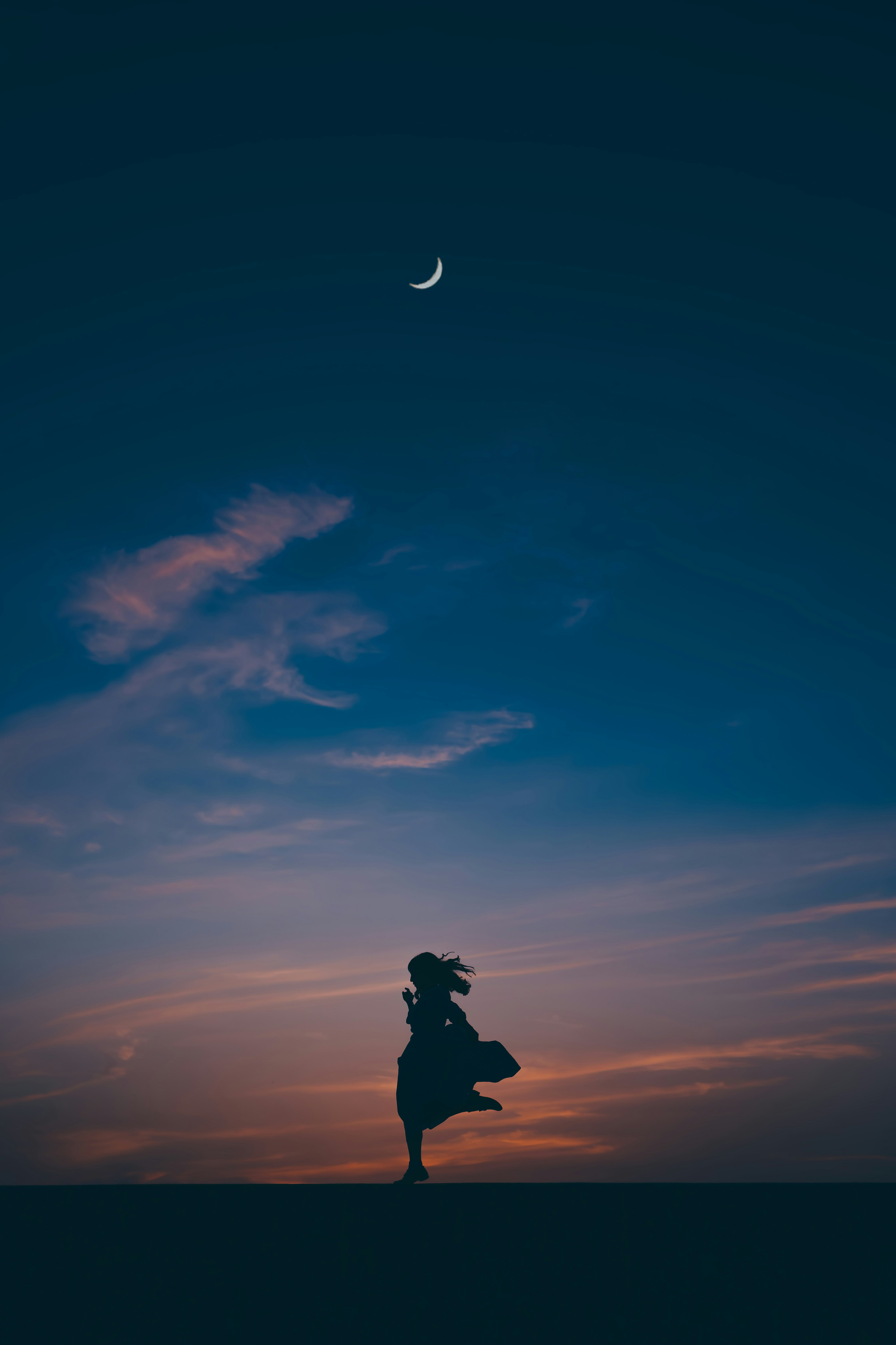 夕焼け空を背景に走るシルエットの人物
