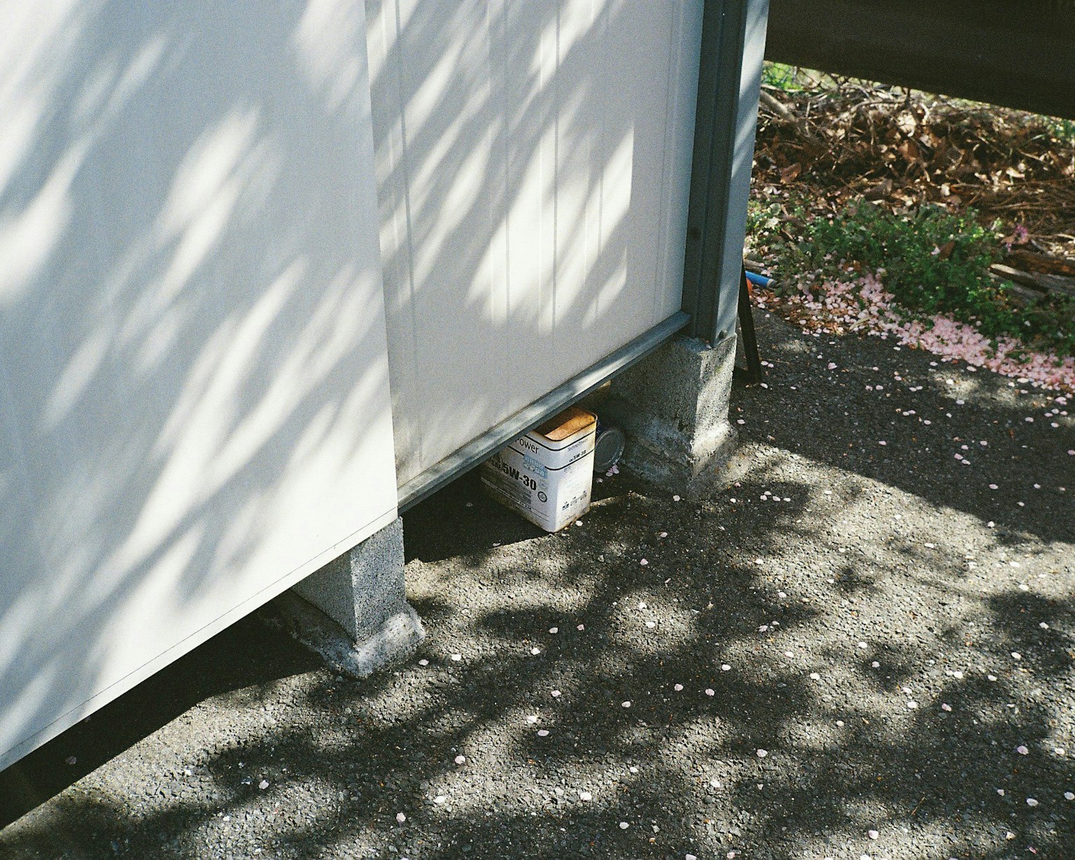 Scene showing a can partially hidden under a white wall casting shadows on the ground