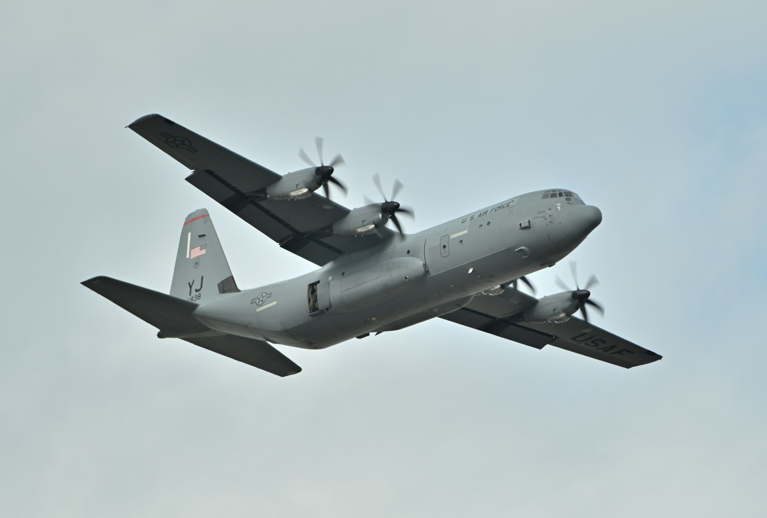 Gray C-130 military transport aircraft flying in the sky
