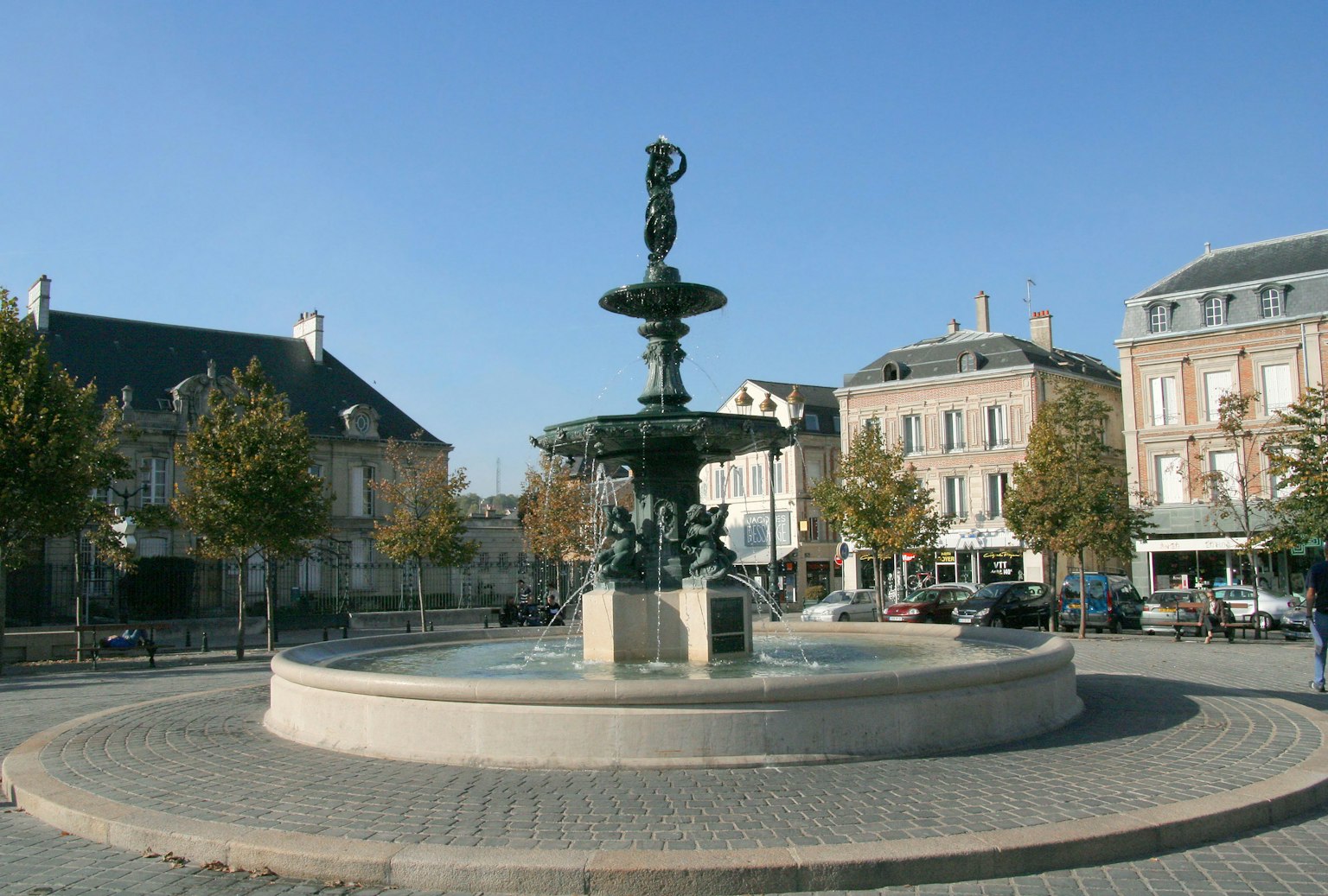 Una bella fontana in una piazza circondata da edifici e alberi