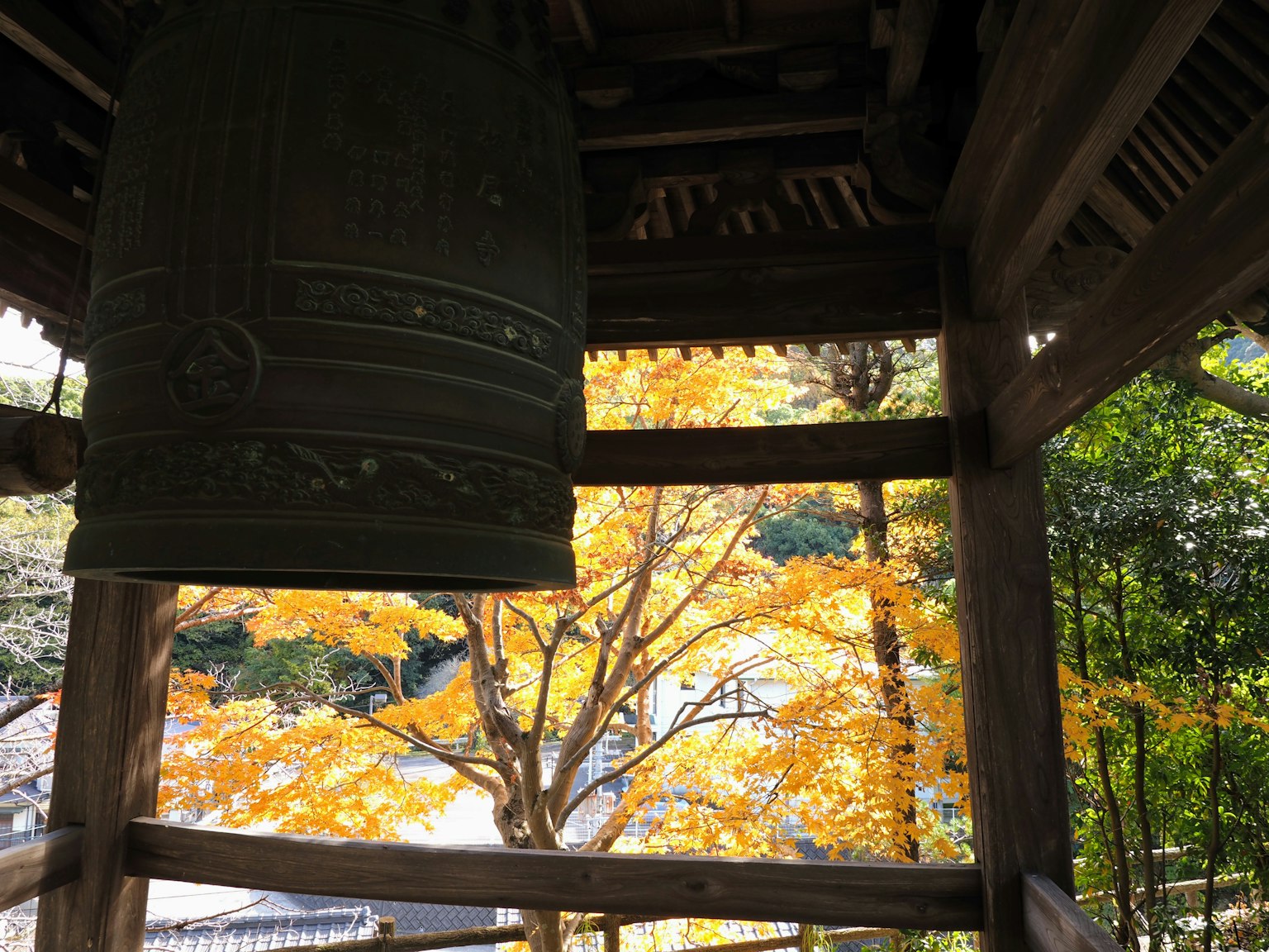 Campana verde in un campanile con foglie gialle d'autunno