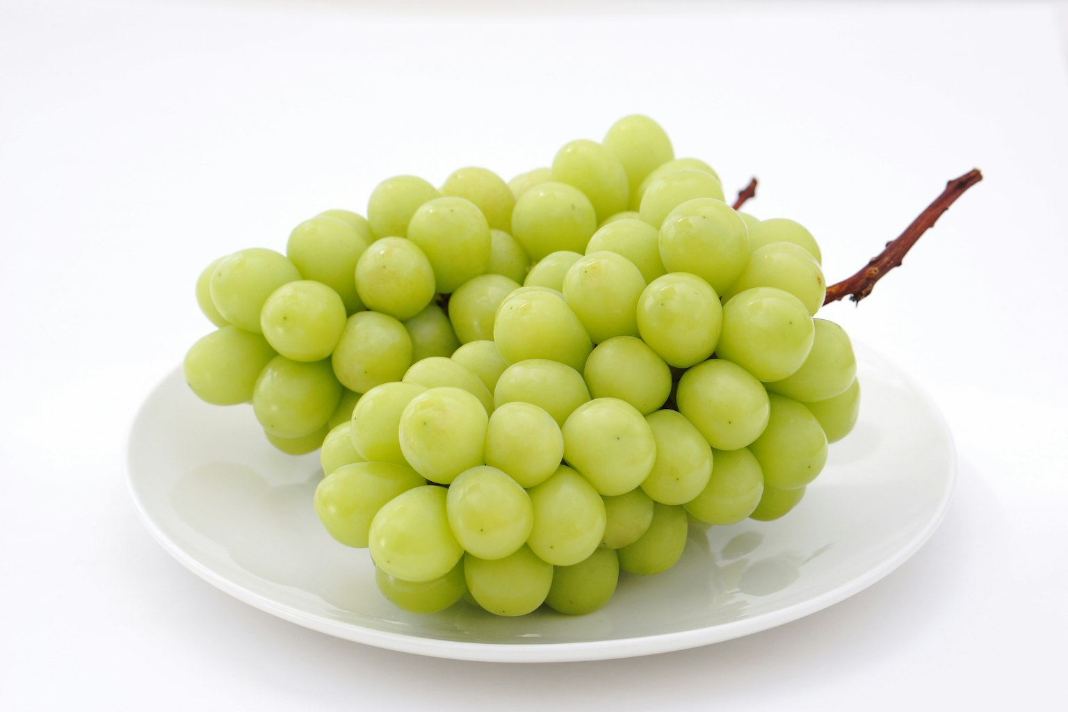 Racimos de uvas verdes frescas en un plato blanco