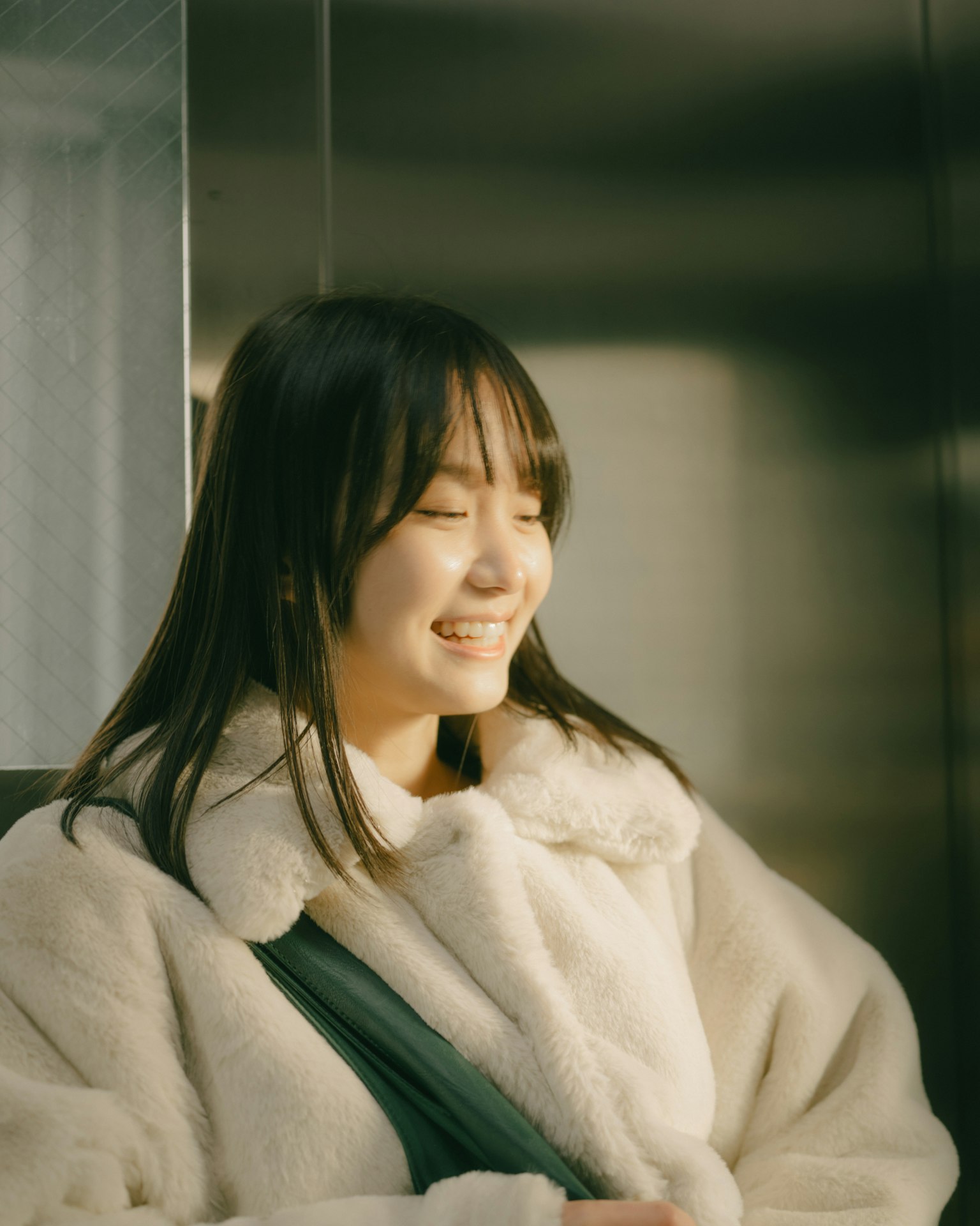 Woman smiling inside an elevator wearing a warm coat