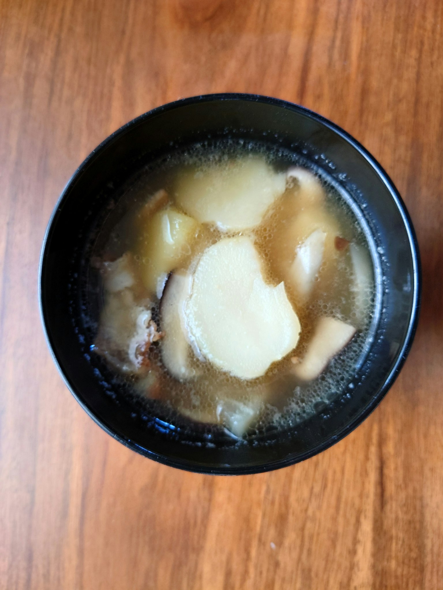 Aufsicht auf Suppe in einer schwarzen Schüssel mit Kartoffeln und Fleisch