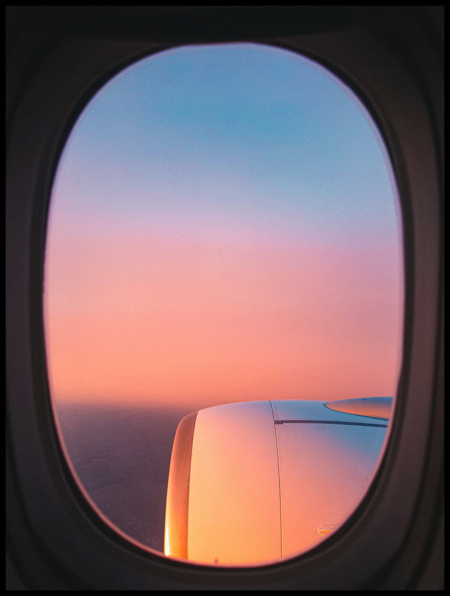 Vista di un cielo colorato al tramonto da un finestrino di aereo con motore