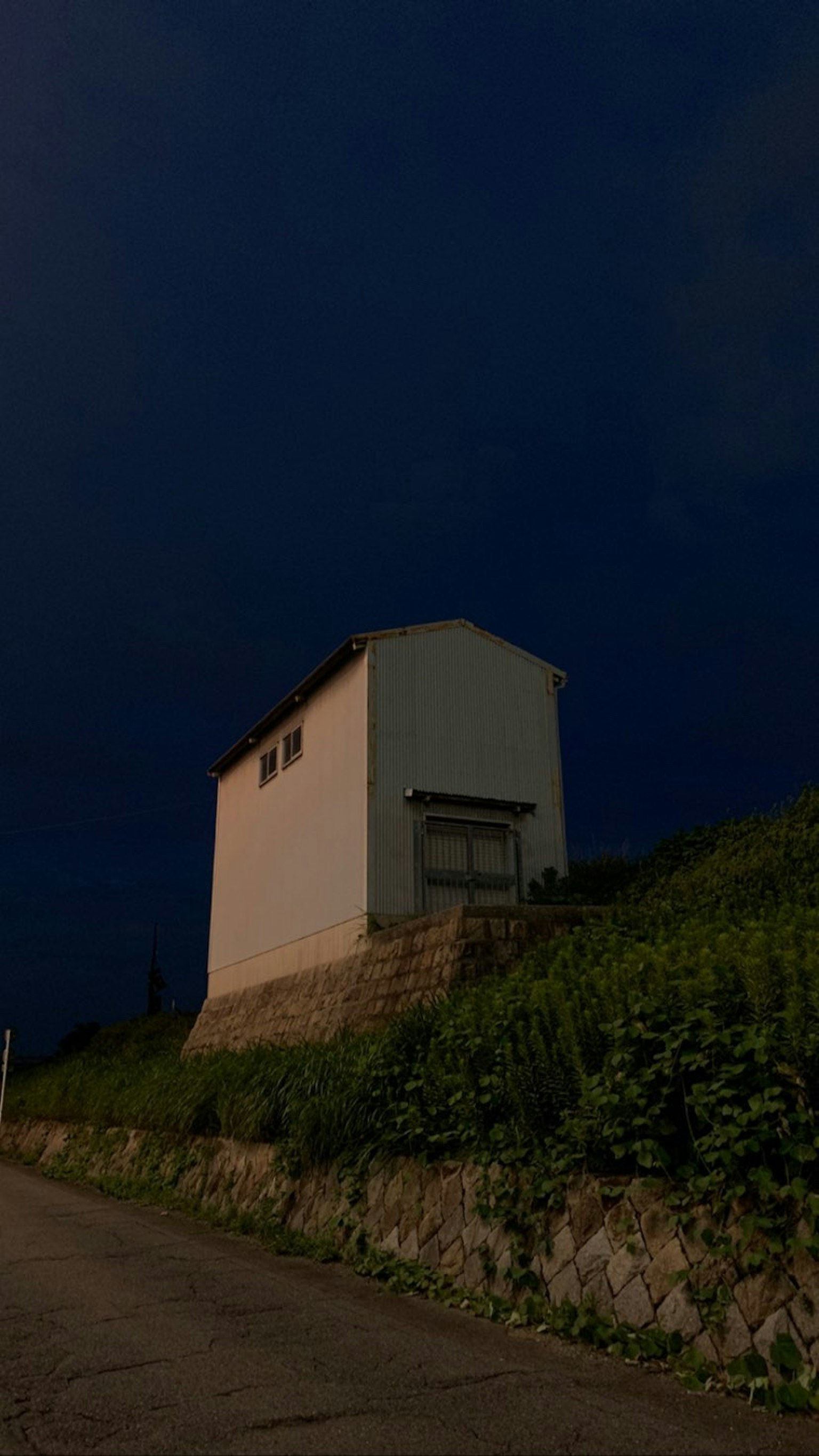 Ein weißes Haus auf einem Hügel unter einem dunklen Himmel