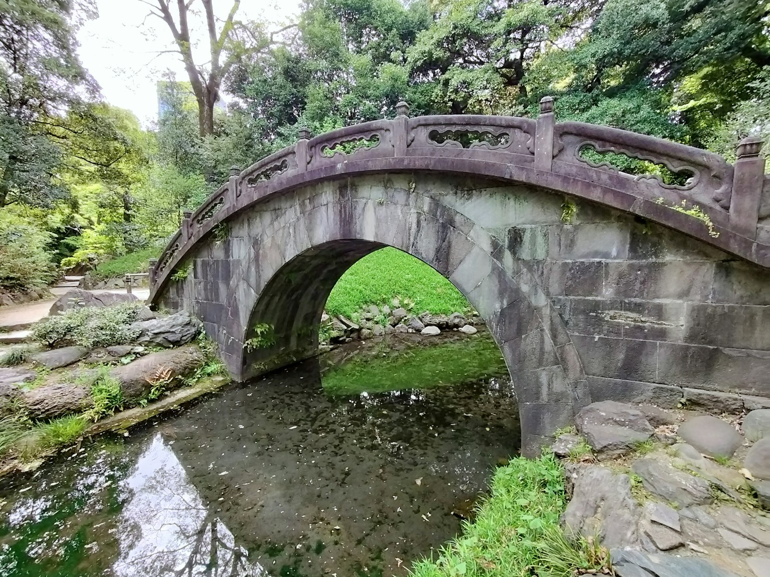 石拱橋與郁郁蔥蔥的綠地和寧靜的池塘