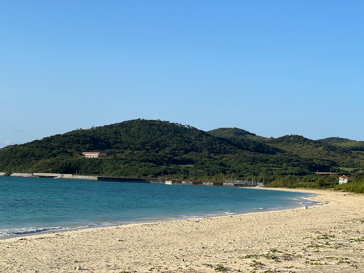 Beach scene with blue sky and calm sea green hills in the background