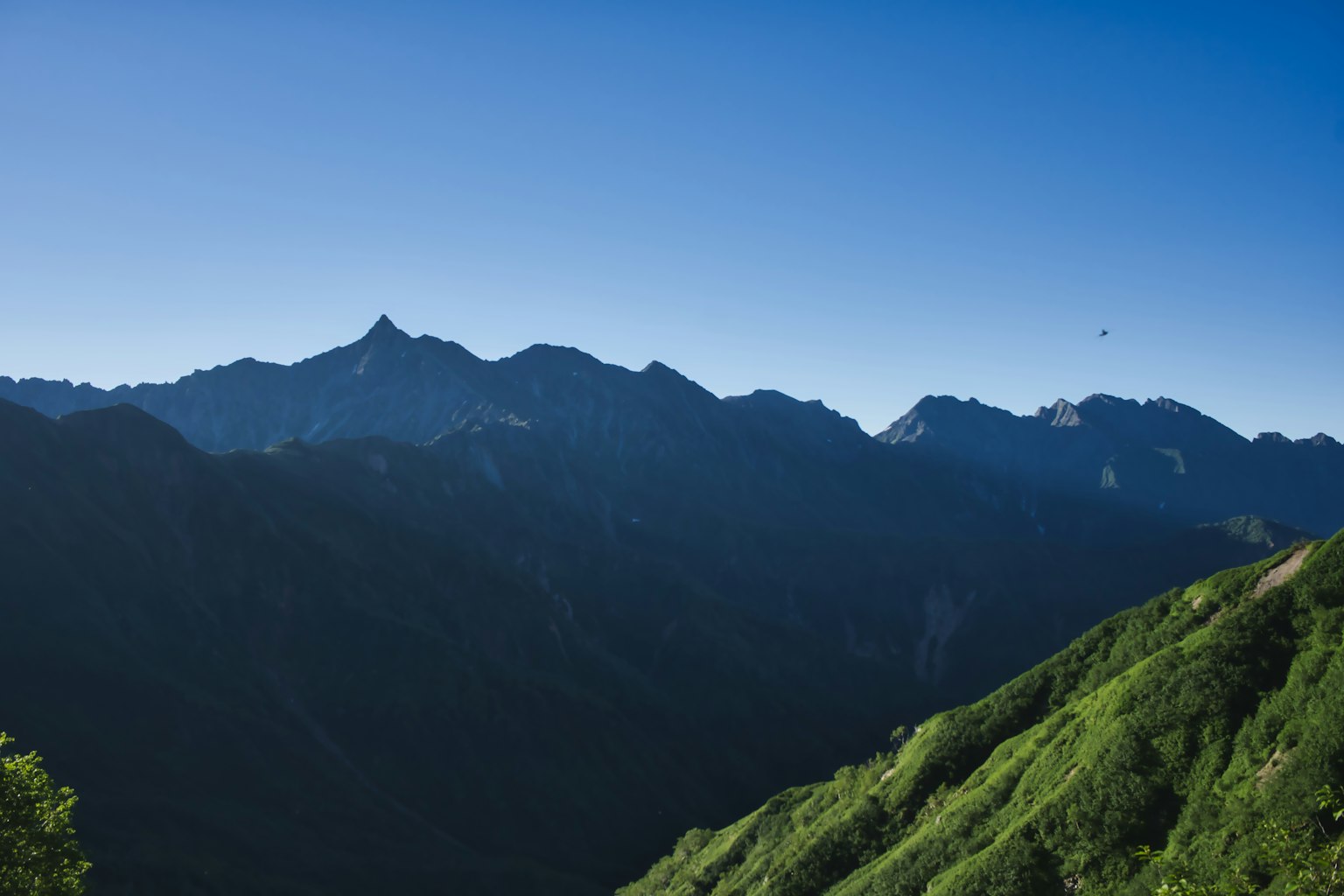 Vista panoramica di montagne verdi sotto un cielo blu chiaro