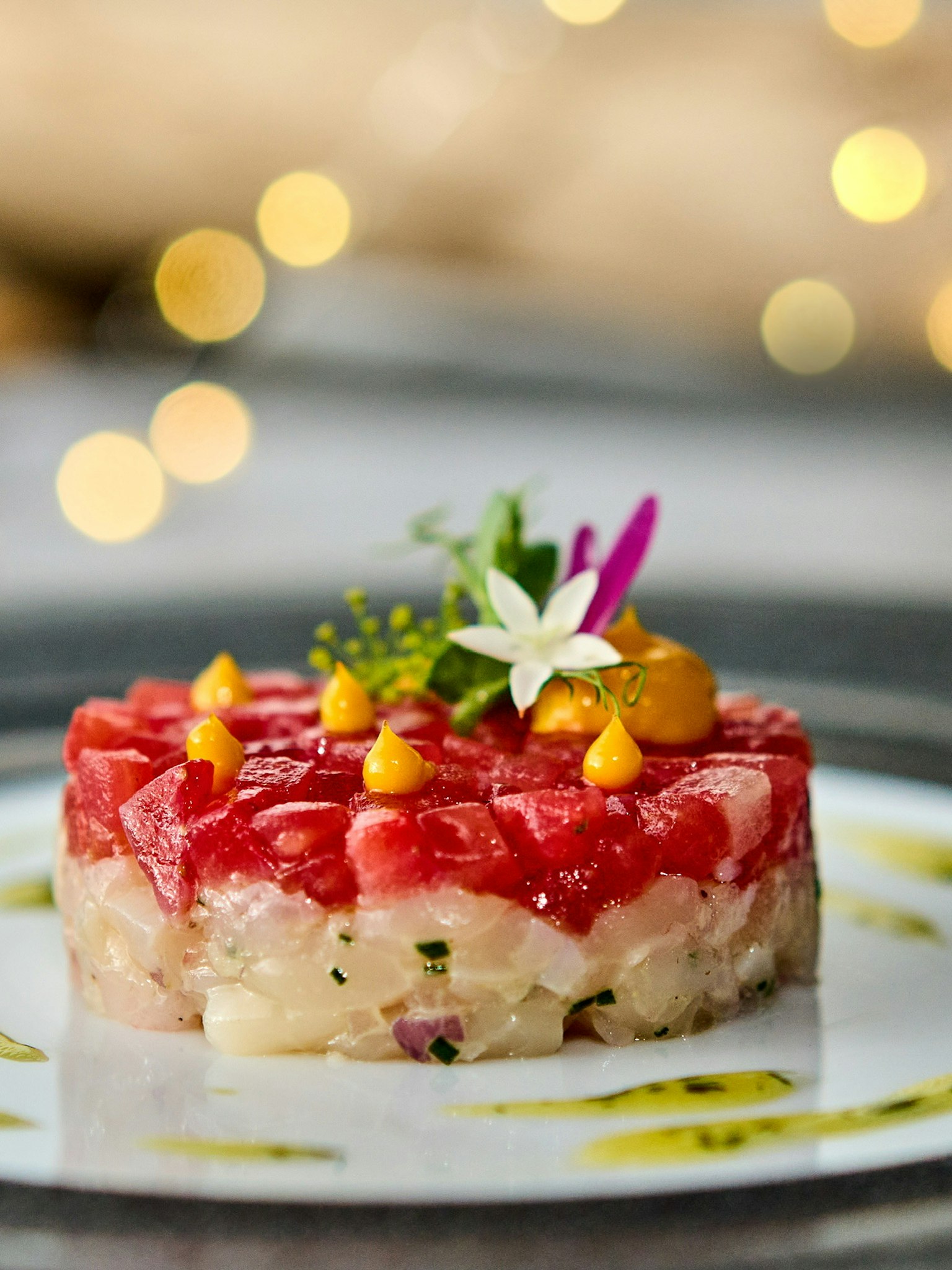 Món tartare sống động được trình bày tinh tế với hoa và sốt