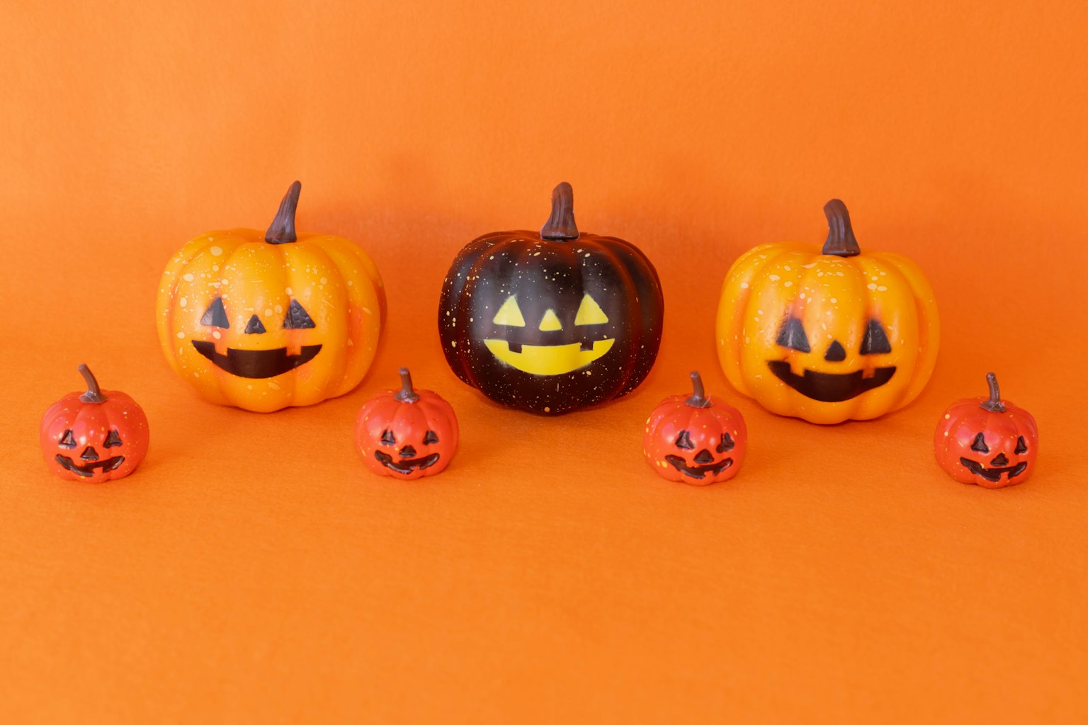 Zucche di Halloween colorate disposte su uno sfondo arancione