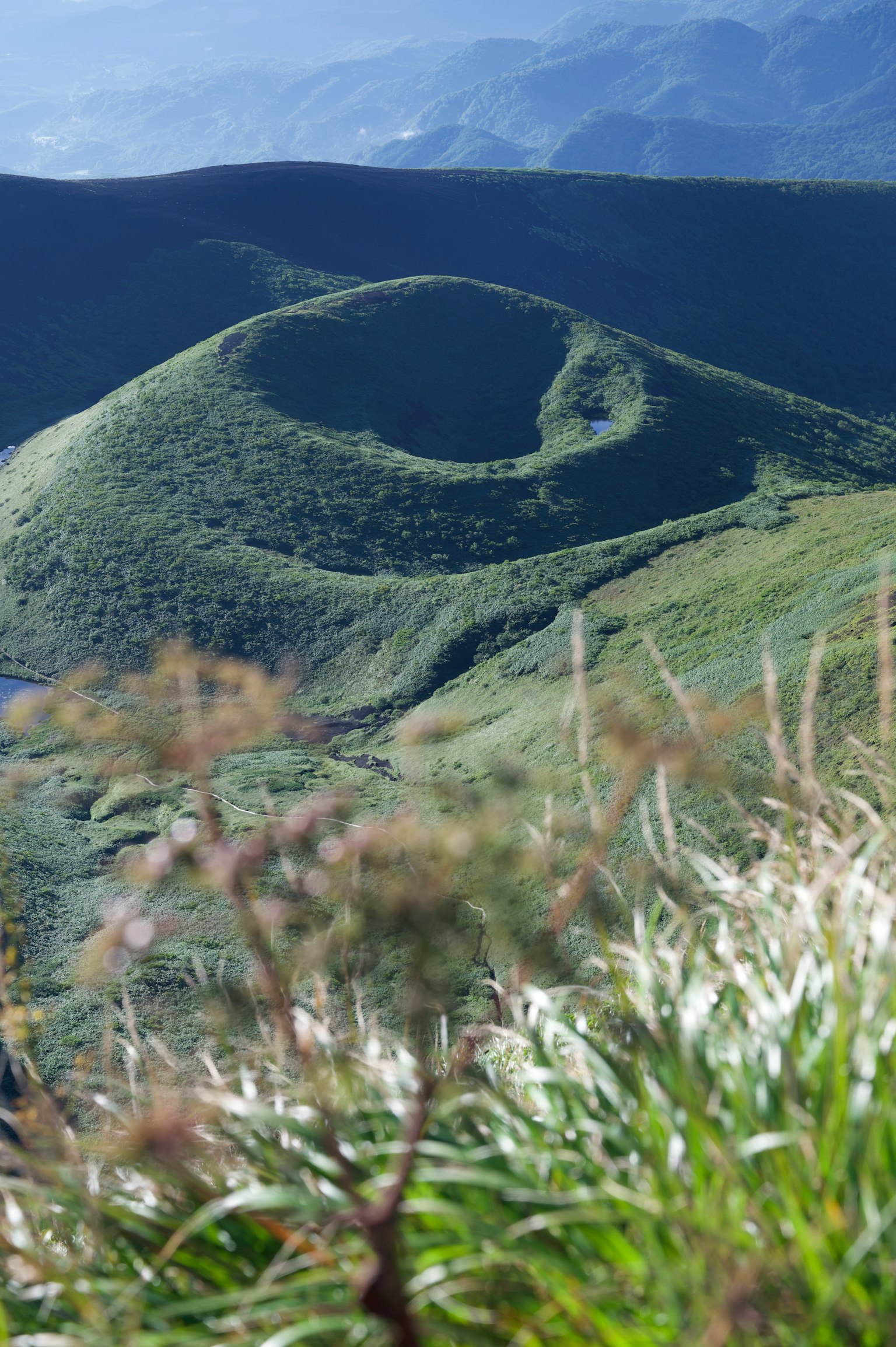Paisaje verde curvado con colinas y montañas distantes