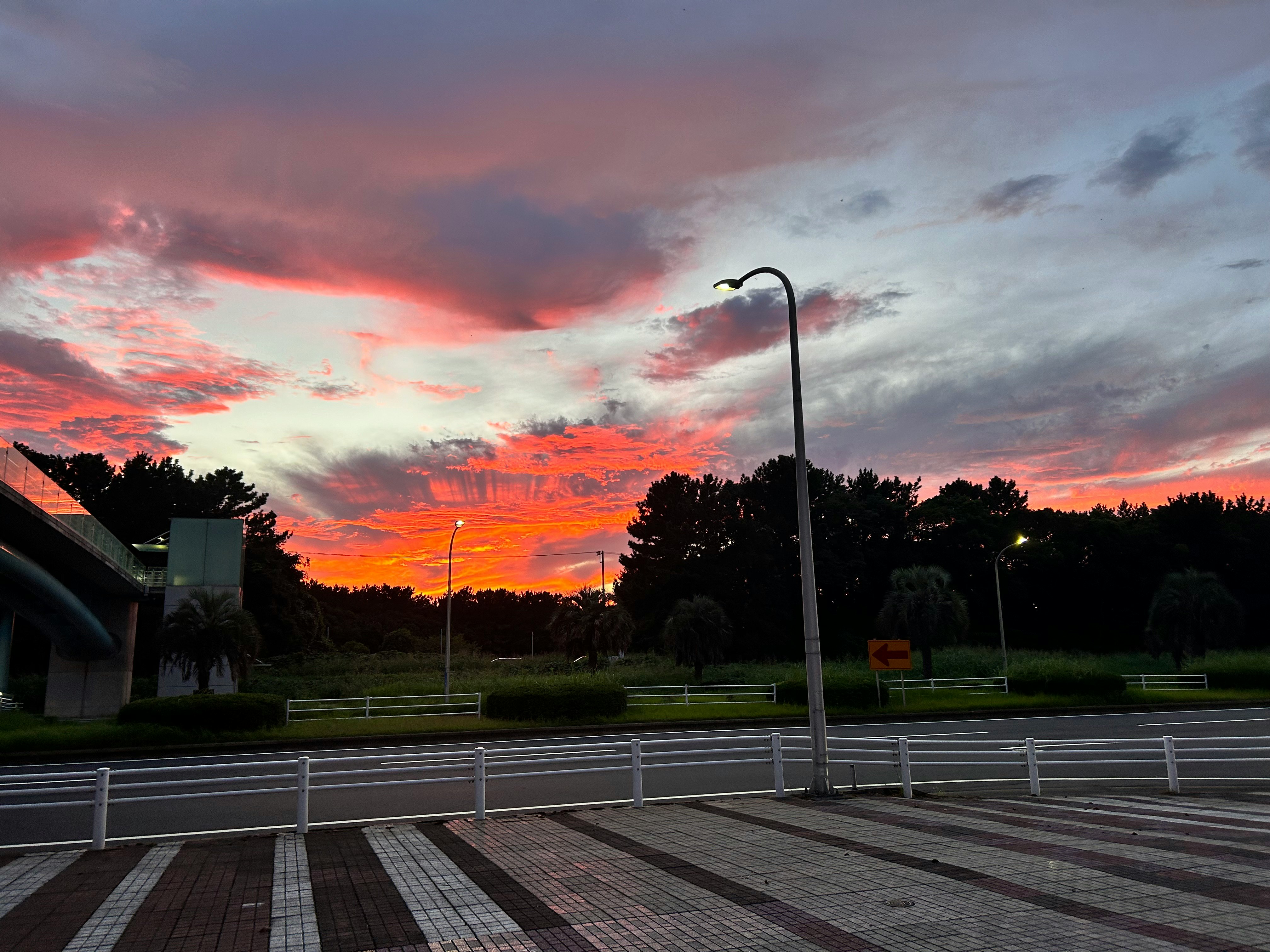 夕暮れの公園と遊歩道、空に広がる雲と赤い光