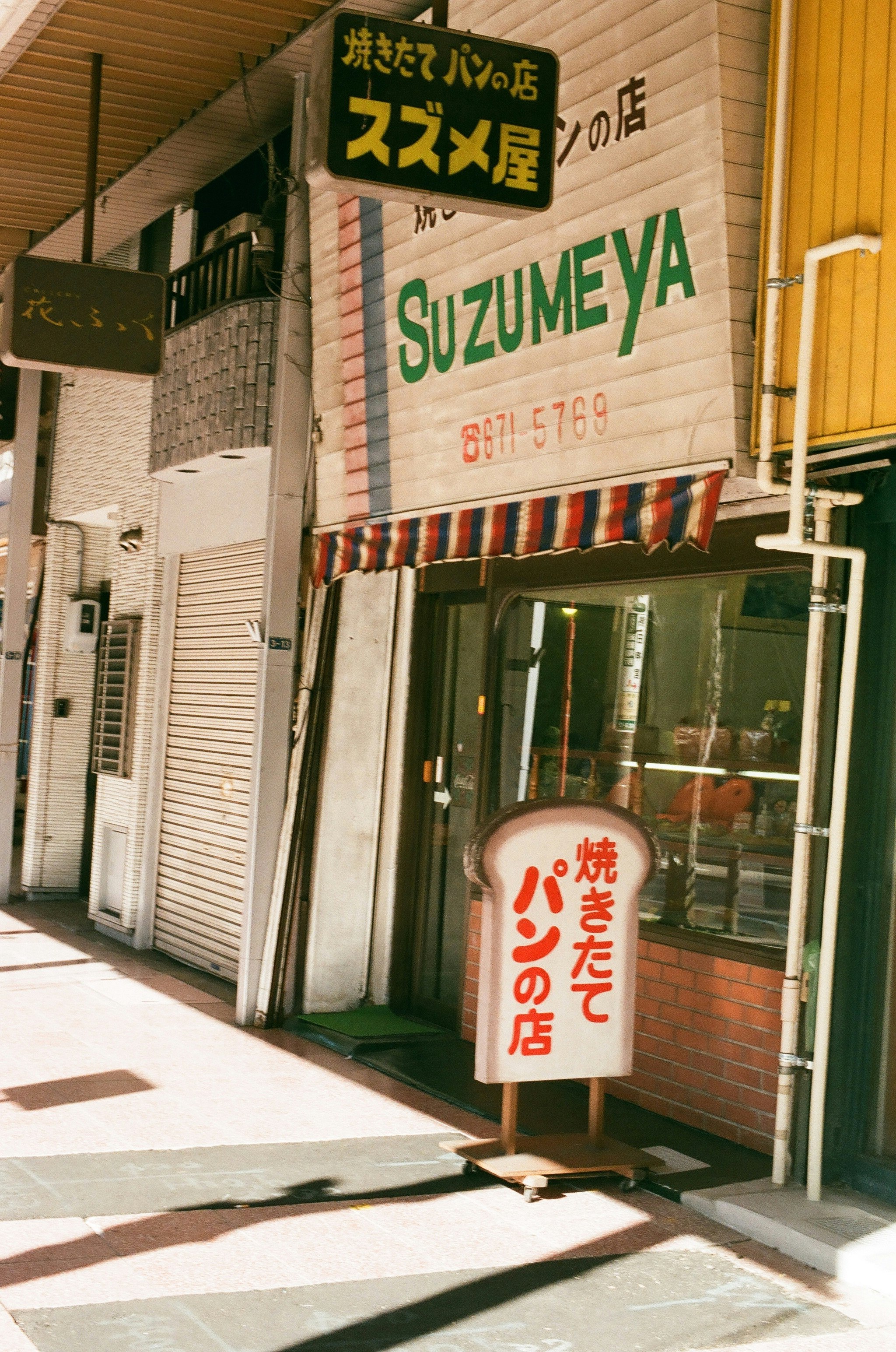 焼きたてパンの店先に並ぶ看板と暖簾のある路地