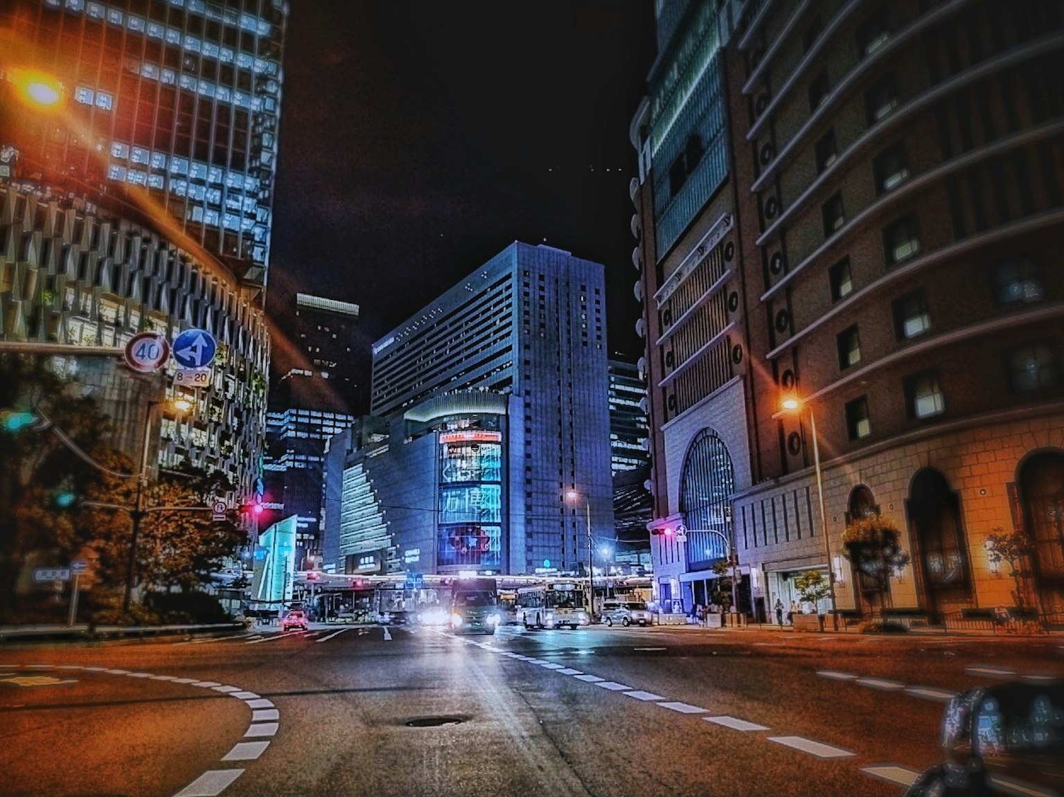Night cityscape featuring tall buildings and cars at an intersection