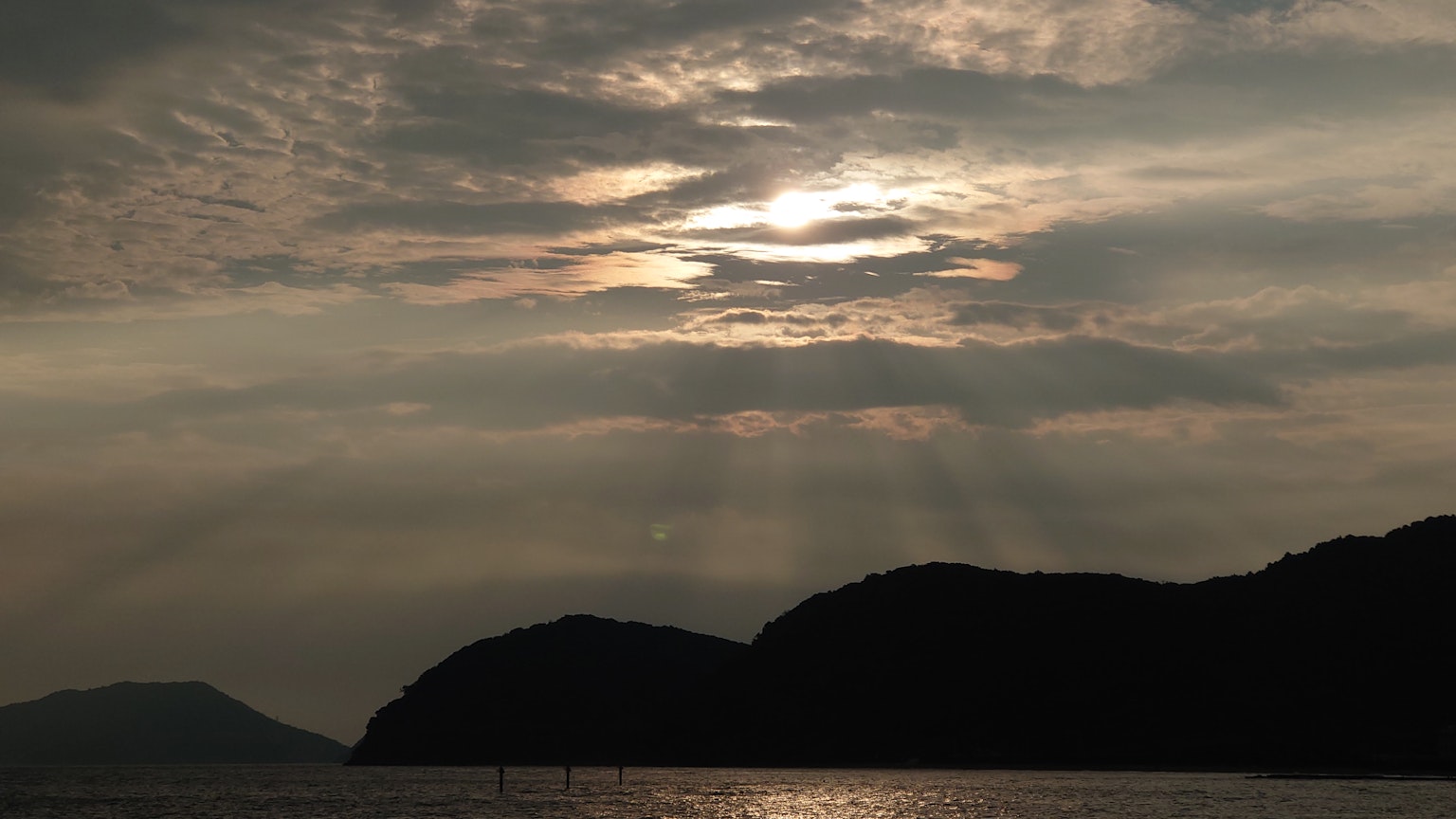 Malersicher Blick auf Berge und ruhiges Meer, beleuchtet vom Sonnenuntergang