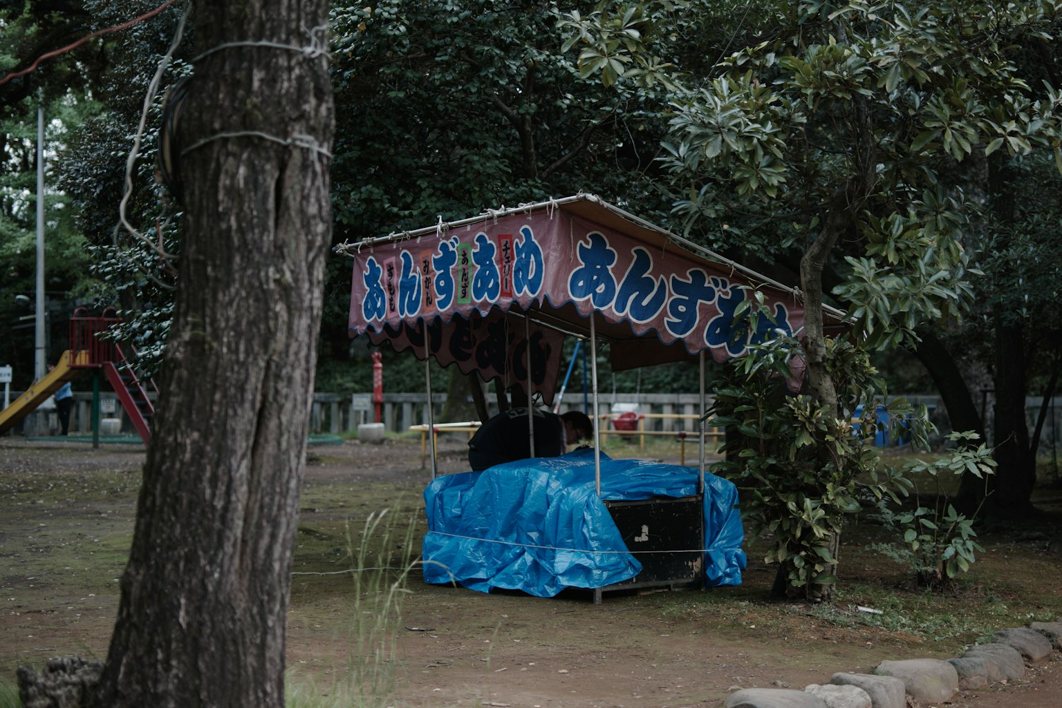 Un puesto cubierto de azul en un parque rodeado de árboles verdes