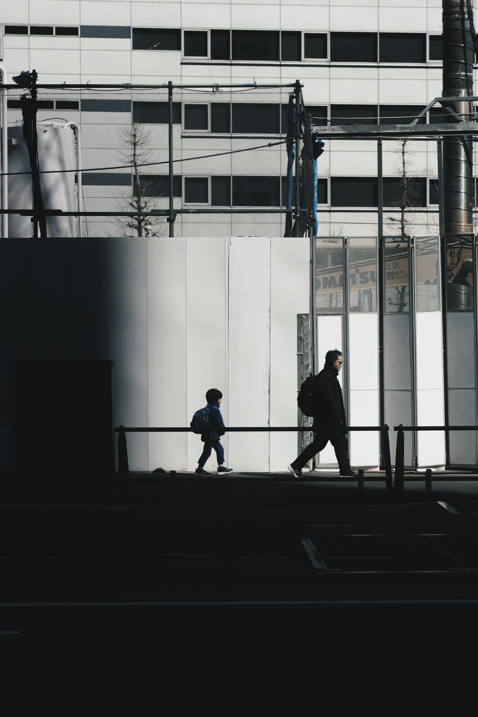 Silhouetten eines Erwachsenen und eines Kindes, die vor einem Gebäude gehen