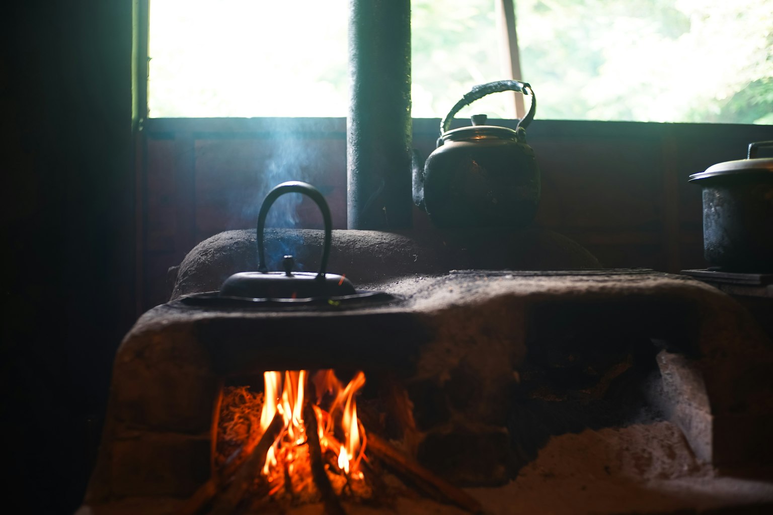 Dapur tua dengan api menyala di kompor dan panci di atasnya