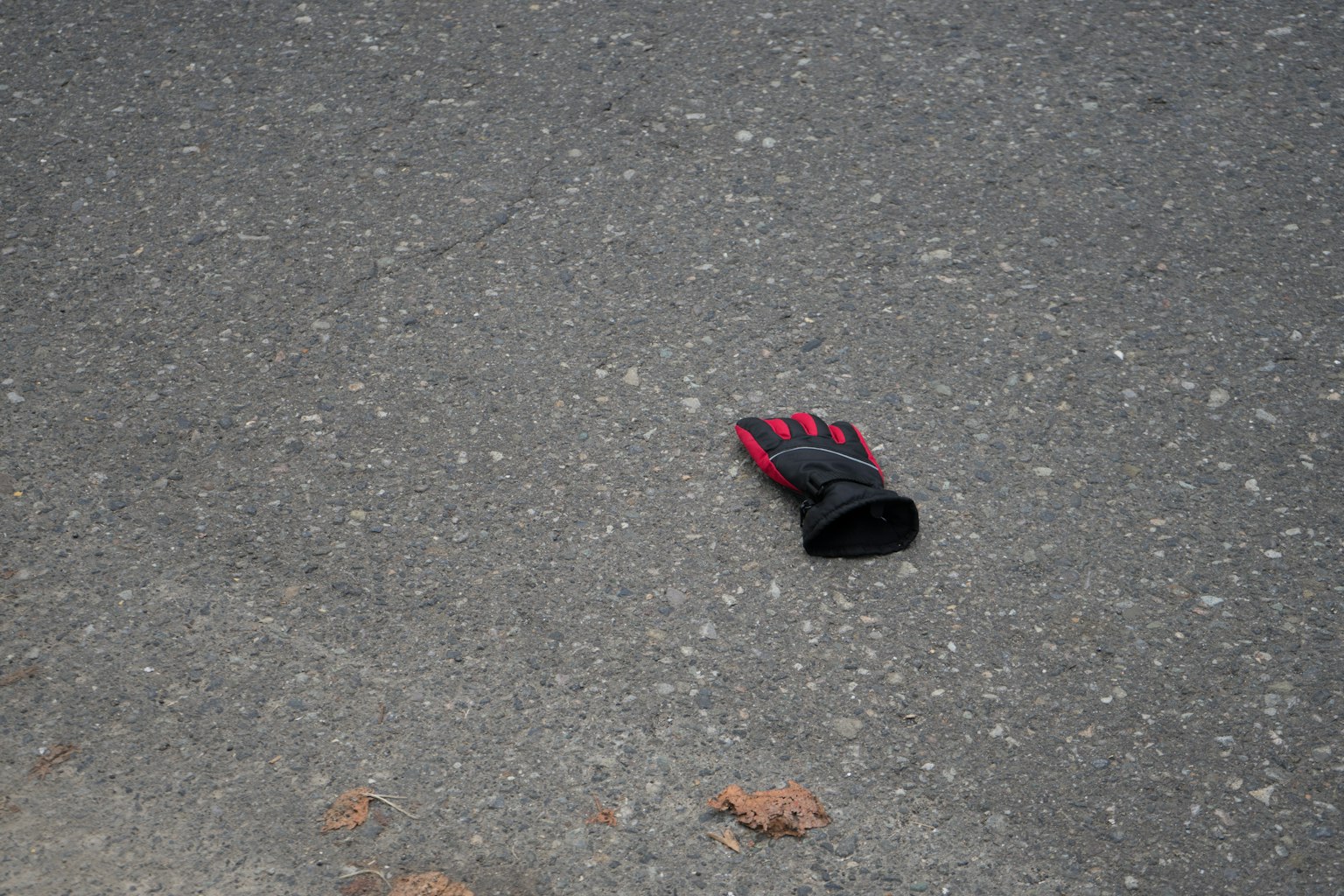 Un gant noir et rouge sur l'asphalte