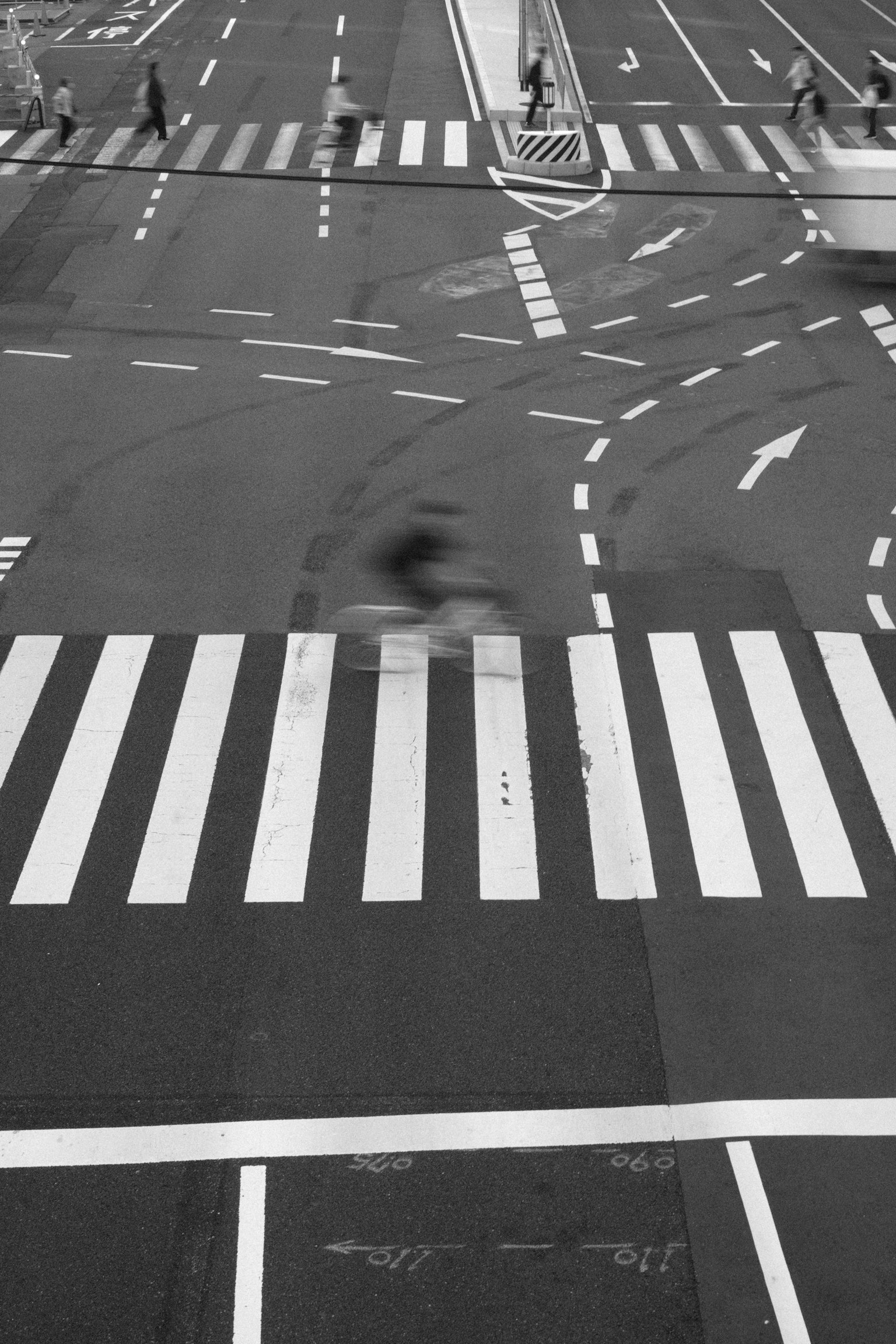 Immagine in bianco e nero di un incrocio con strisce pedonali e movimento del traffico