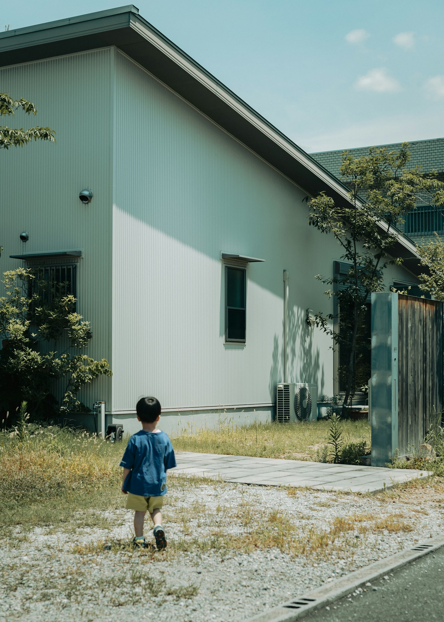 เด็กเล็กเดินอยู่หน้าบ้านในสภาพแวดล้อมที่เงียบสงบ