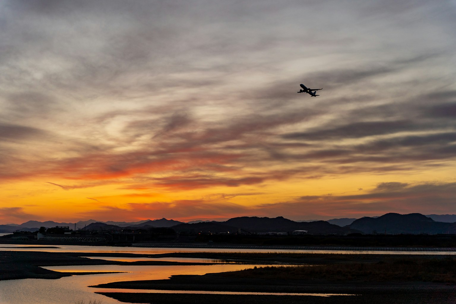 Un paesaggio bellissimo con un aereo che vola contro un cielo al tramonto