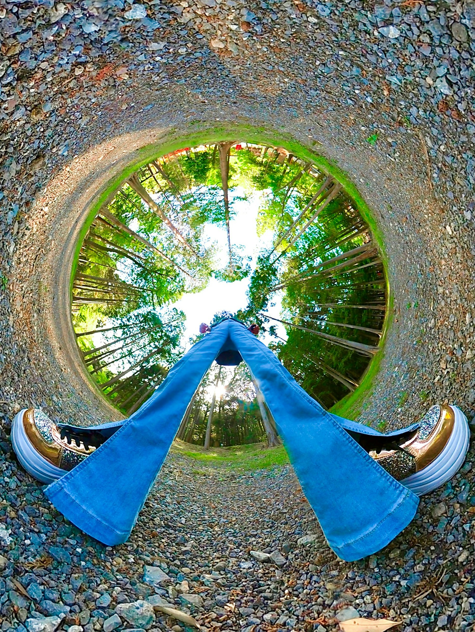 Piedi in jeans blu con una prospettiva circolare che mostra la natura circostante
